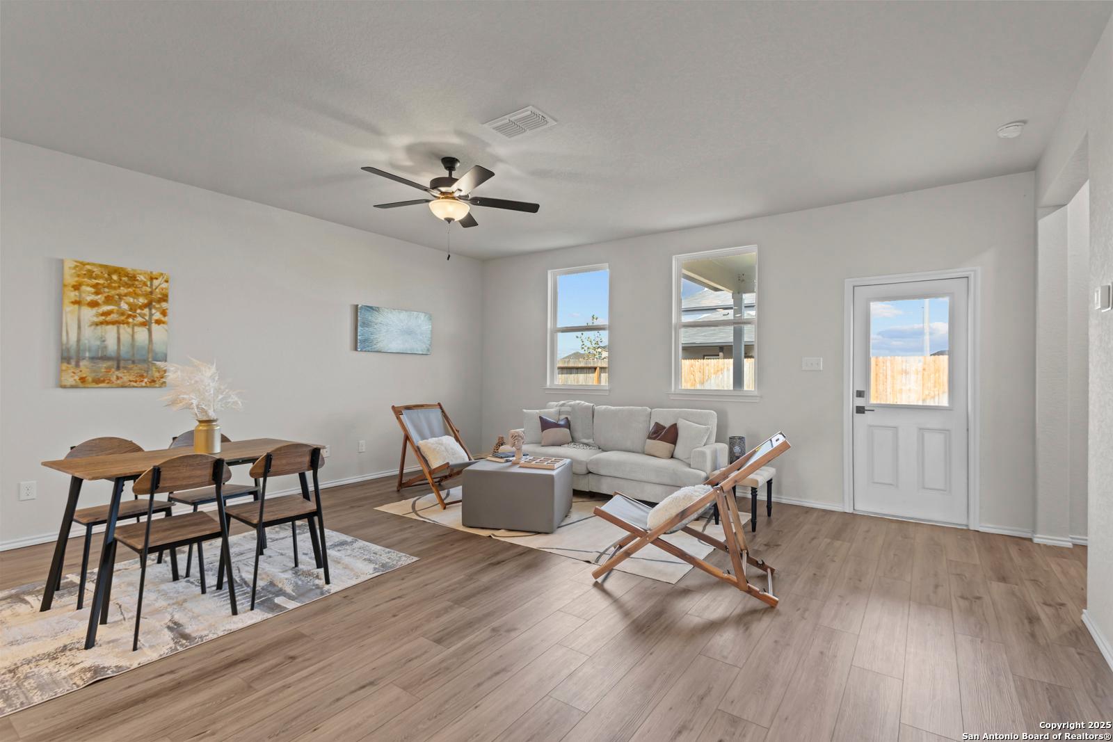 Modern dining-living area with wood table, gray sectional sofa, ceiling fan in 3-bed Davidson Homes The Douglas C, Seguin, TX