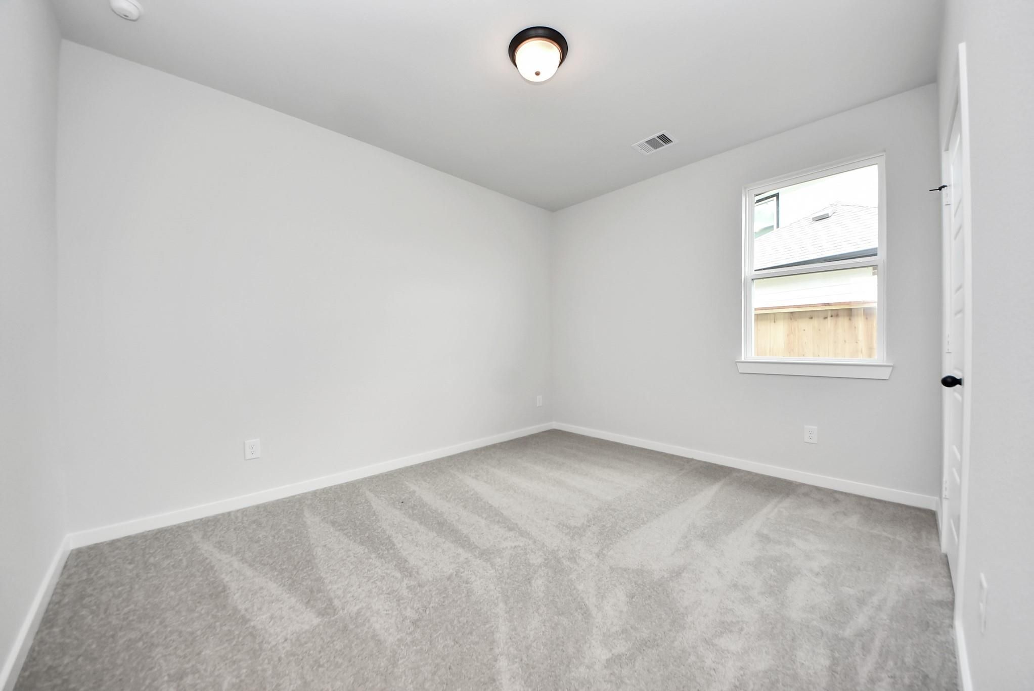 Bright secondary bedroom with plush carpeting in The Daphne F floor plan at Sundance Cove, Crosby, Texas.