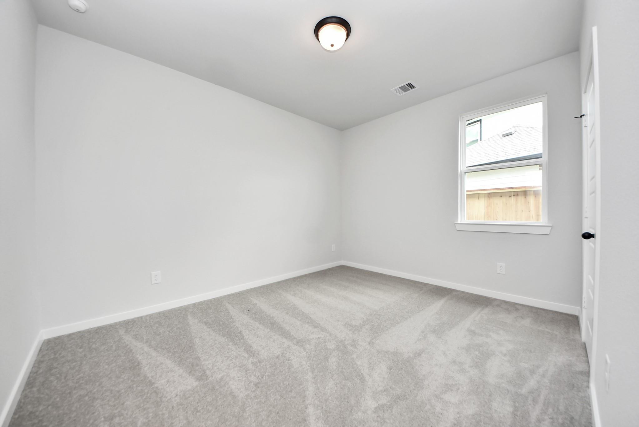 Bright secondary bedroom with plush carpeting in The Daphne F floor plan at Sundance Cove, Crosby, Texas.