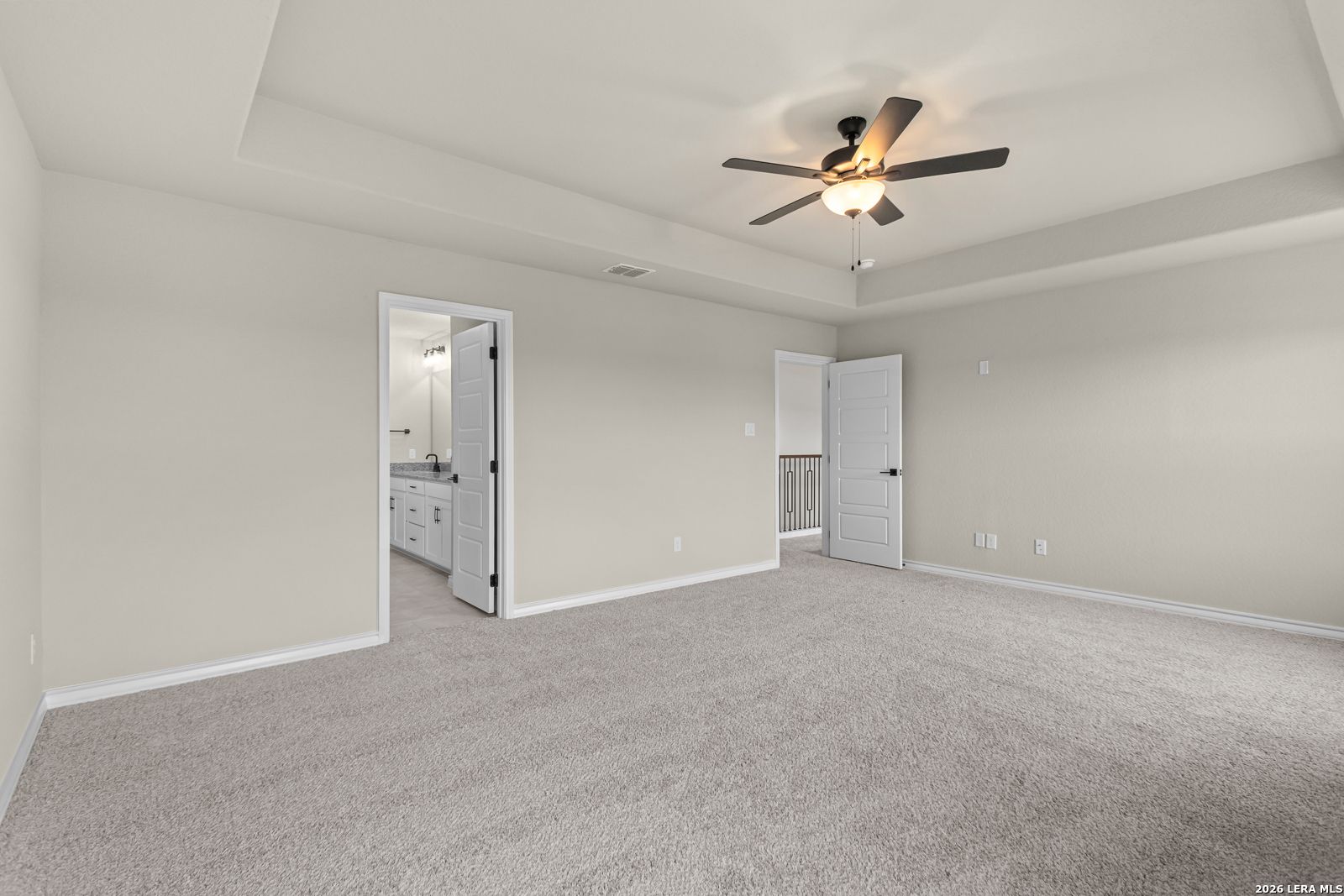 Spacious primary bedroom with tray ceiling and ceiling fan in The Danbury H floor plan at Potranco Oaks, Castroville.