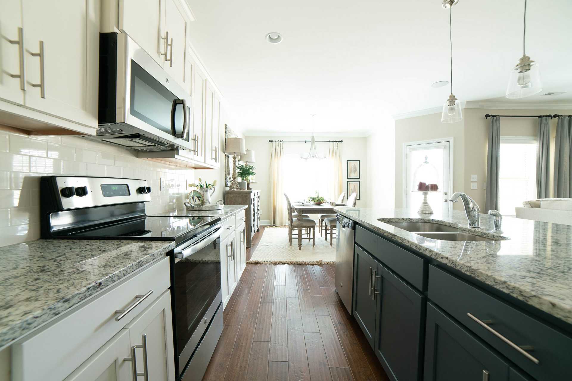 Spacious open-concept kitchen at The Dairy at Oak Grove in South Huntsville AL with white cabinets granite island stainless appliances and dining nook