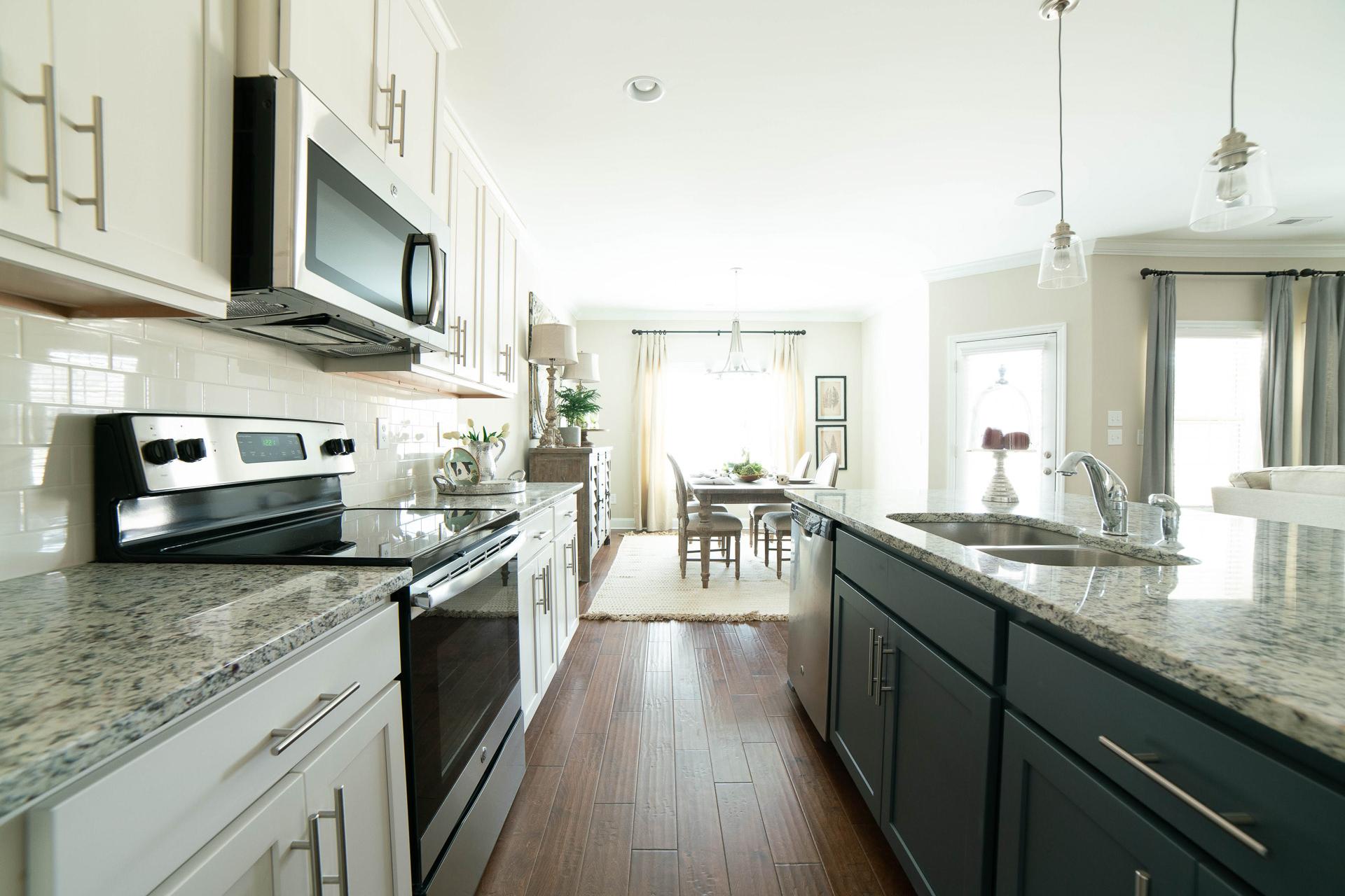 Spacious open-concept kitchen at The Dairy at Oak Grove in South Huntsville AL with white cabinets granite island stainless appliances and dining nook