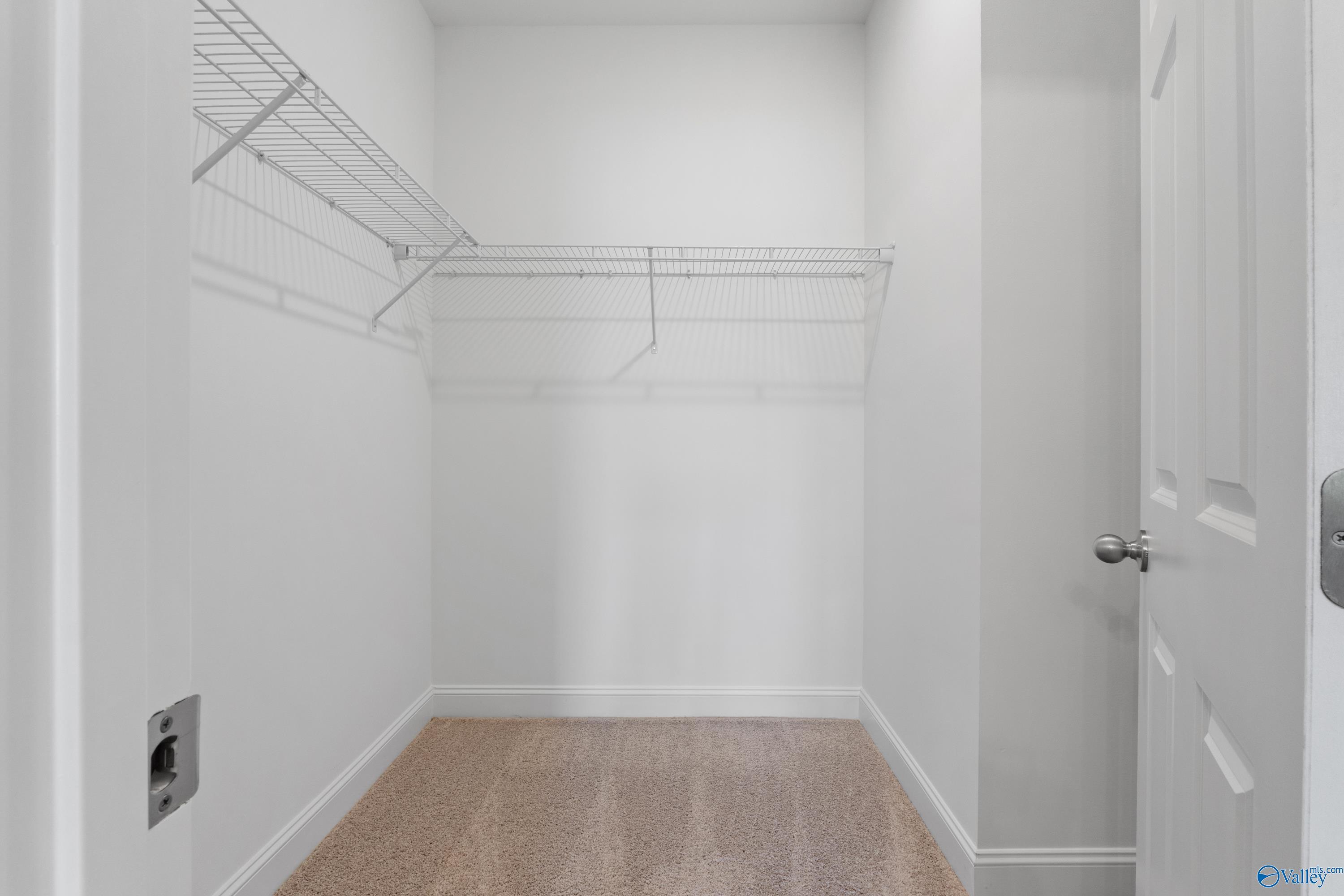 Spacious walk-in closet with wire shelving and beige flooring in The Asheville C master suite, Davidson Homes, Athens, Alabama