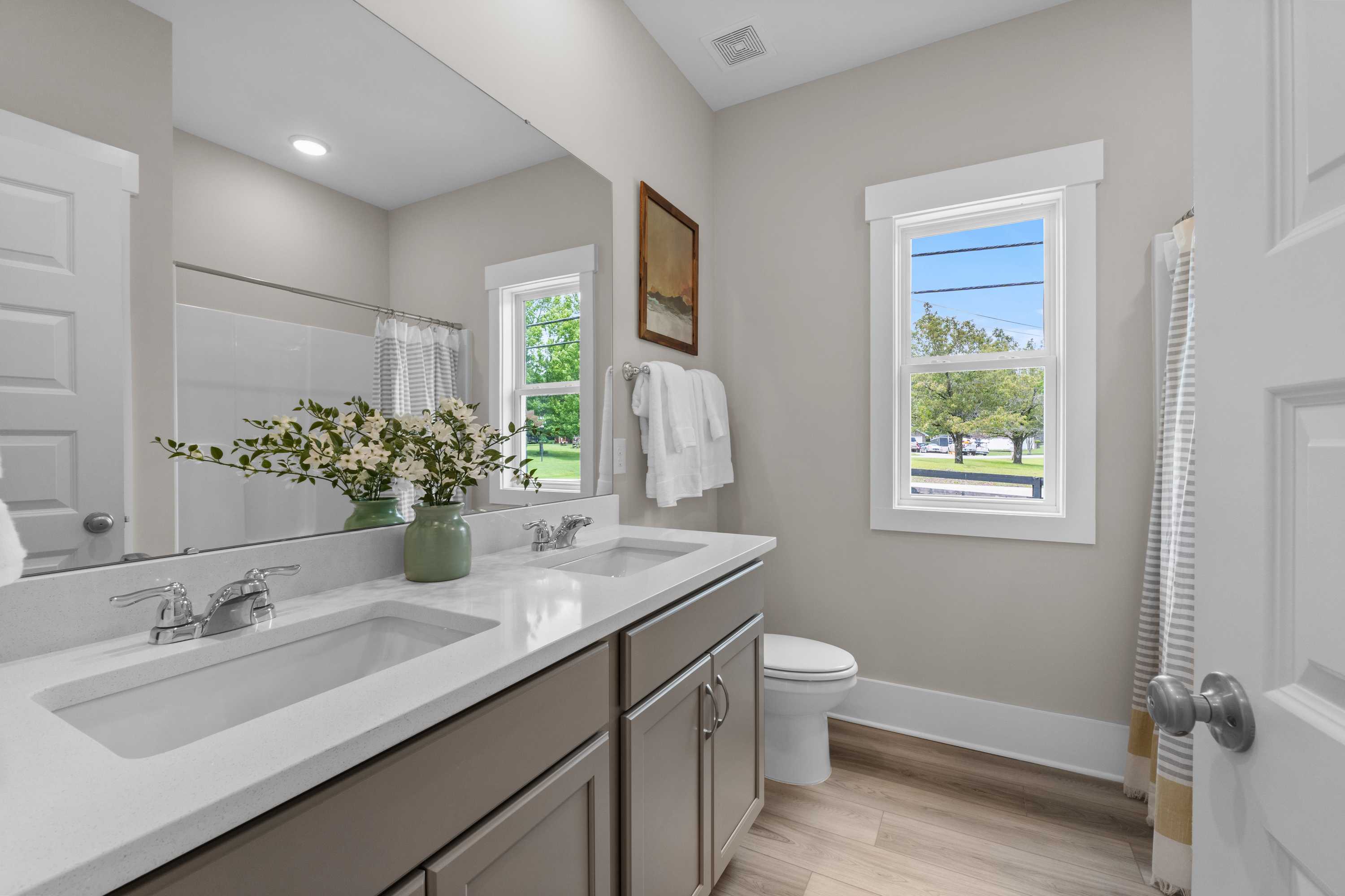 Bright modern bathroom at The Highlands in Arab Alabama with double vanity, walk-in shower, and scenic window view