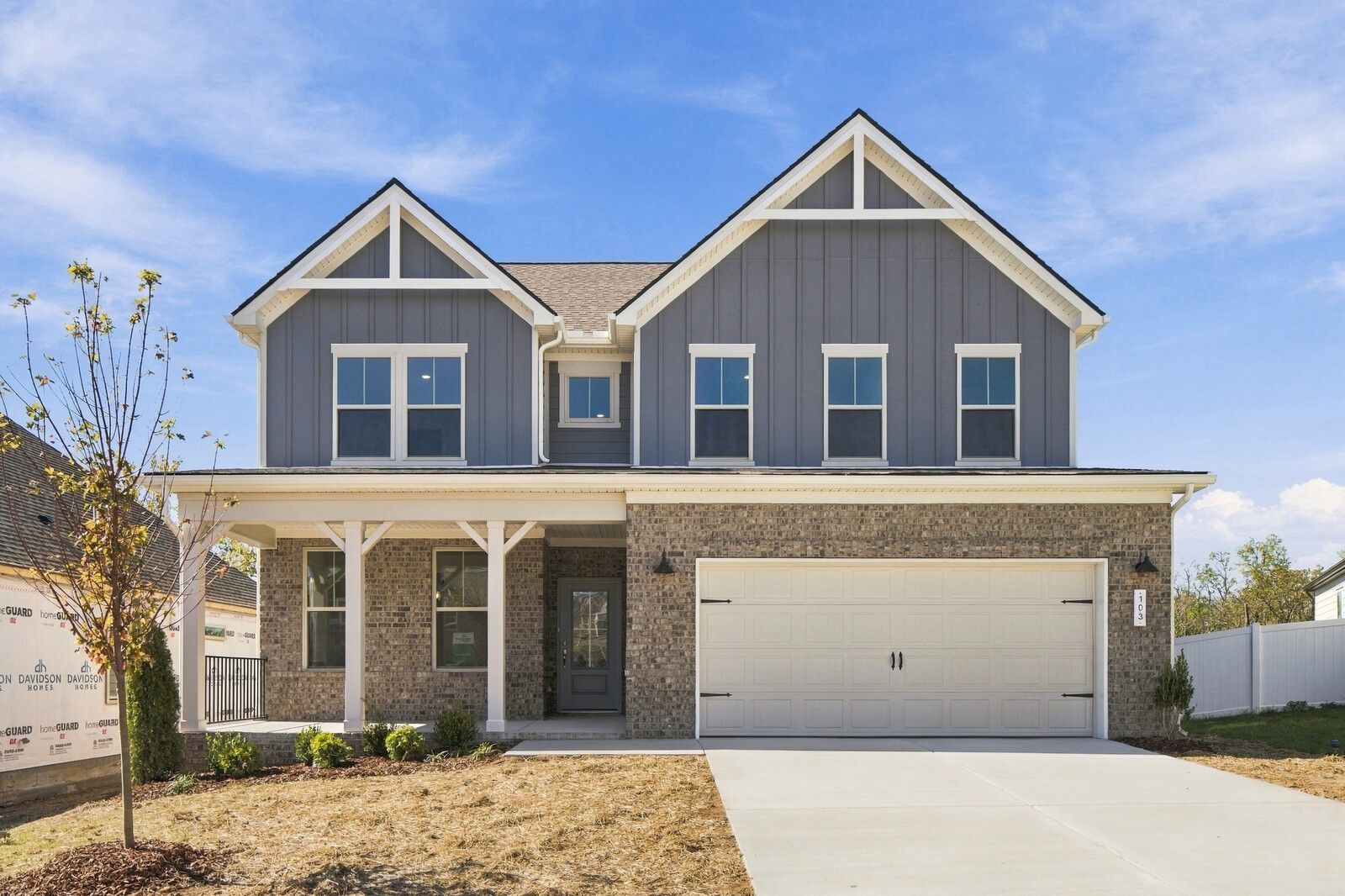 Two-story gray and brick new construction home with covered porch and 2-car garage by Davidson Homes in Gallatin, Tennessee