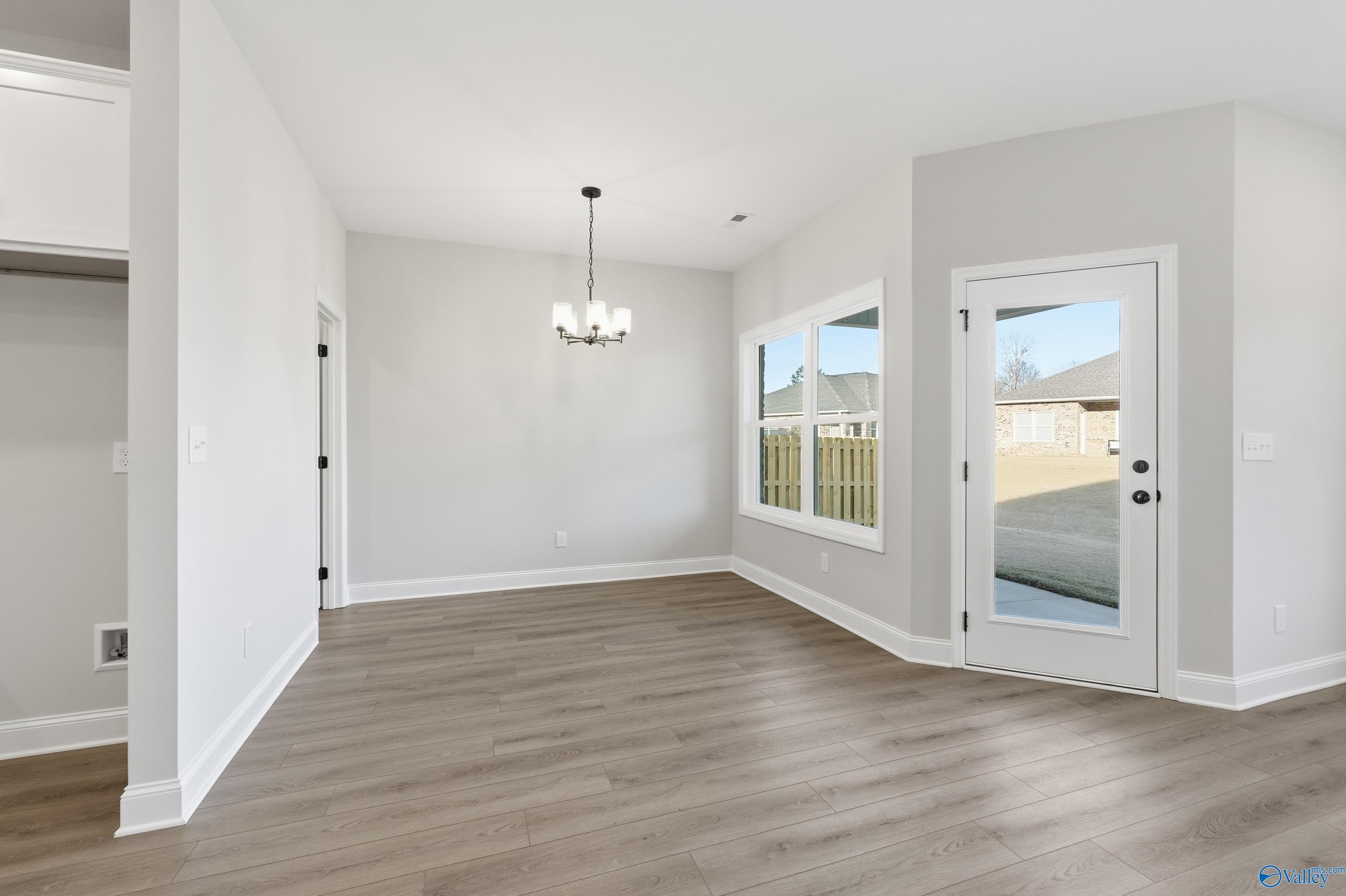 Bright dining room with chandelier, large windows, hardwood floors in The Daphne D by Davidson Homes, Arab, Alabama