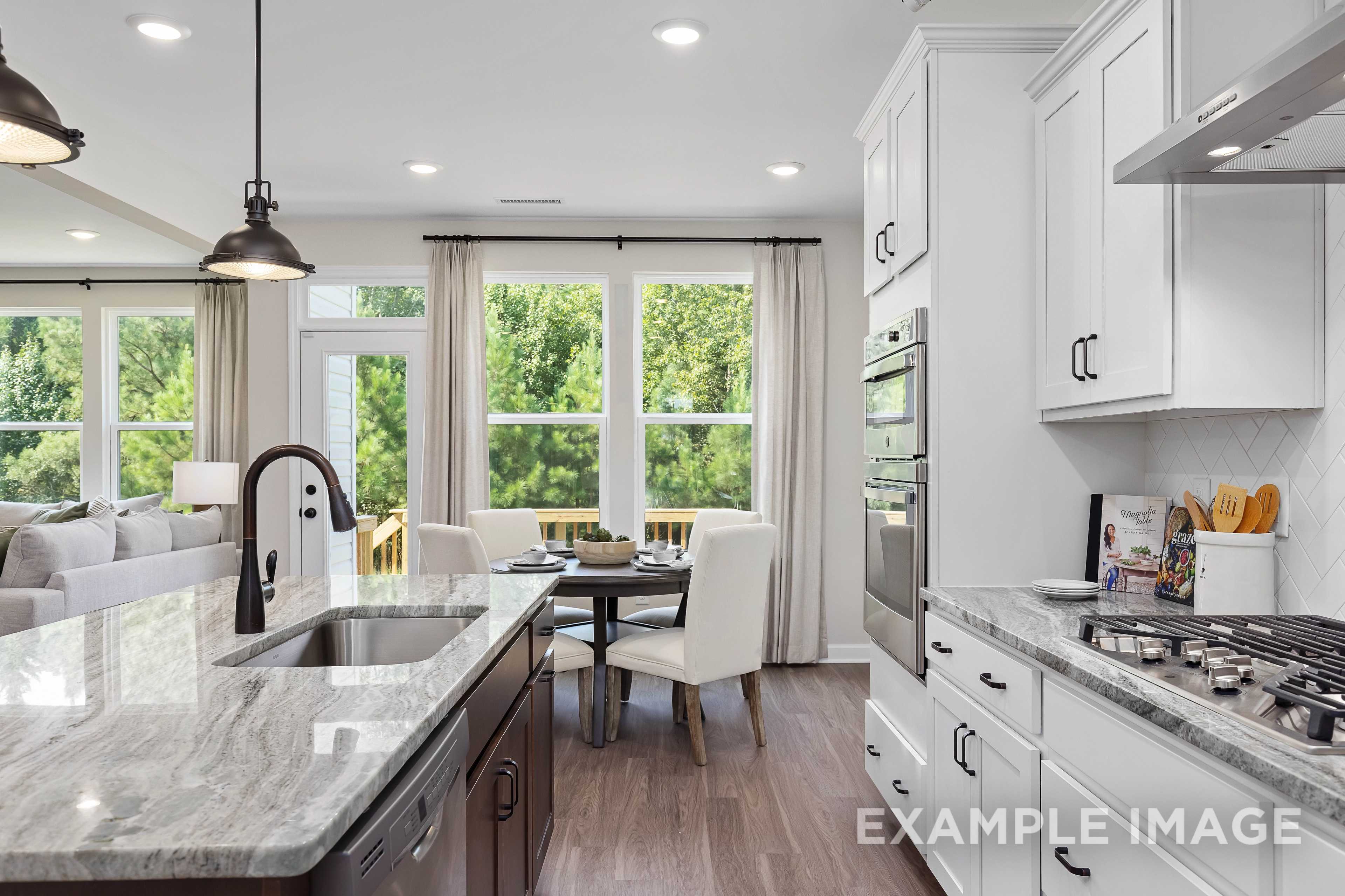 Spacious open-concept kitchen in The Willow B with white shaker cabinets, quartz counters, gas range, and sunny dining nook