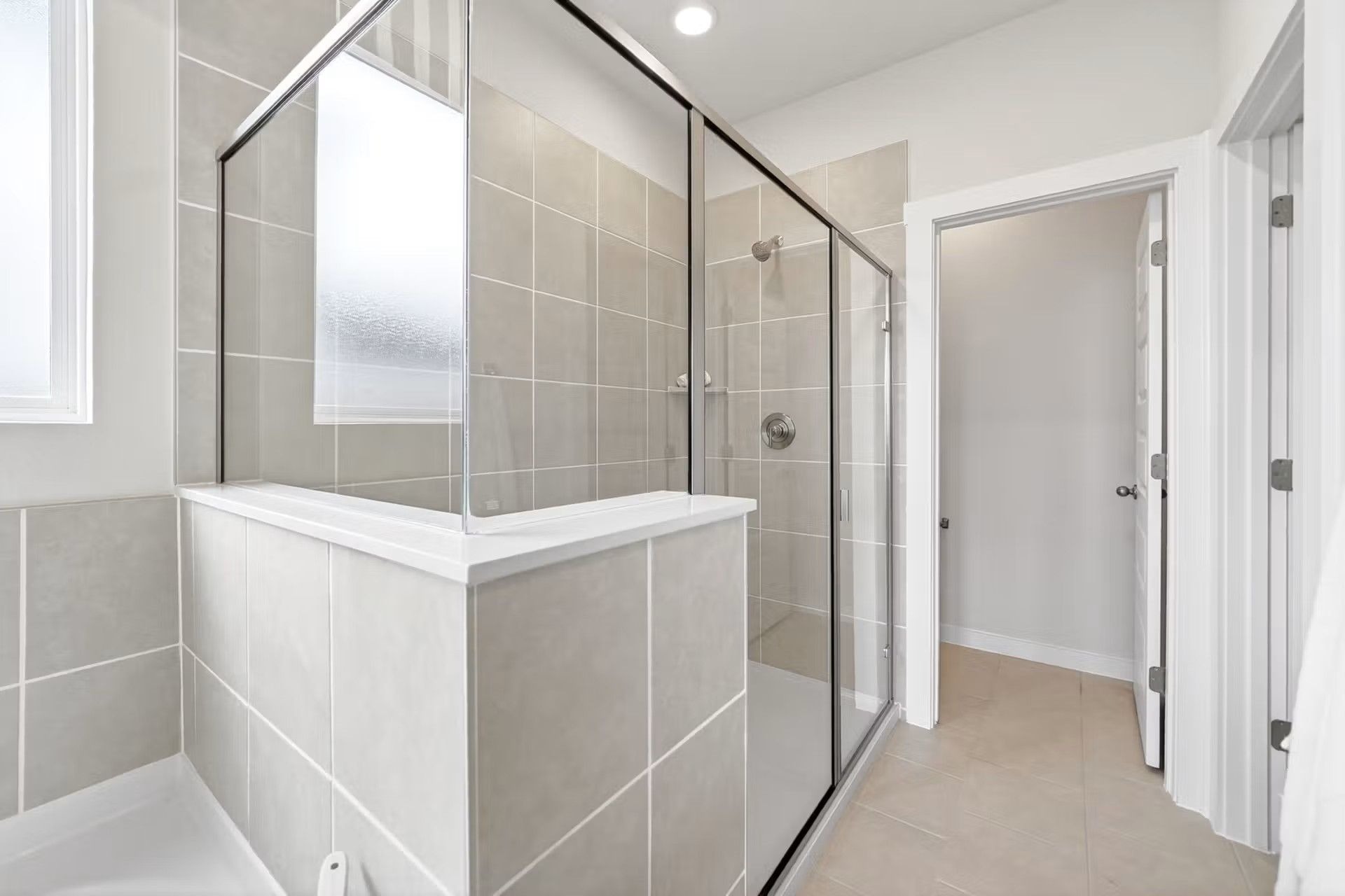 Modern walk-in shower with neutral tile surround in the Laurel I floor plan by Davidson Homes in Heartland, Texas.