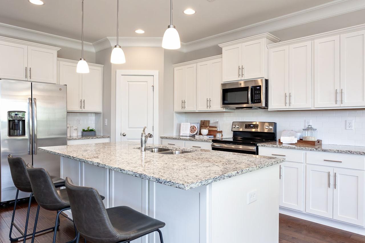Bright kitchen with white cabinets, granite island, stainless appliances and bar stools at Laurenwood Preserve in Madison AL