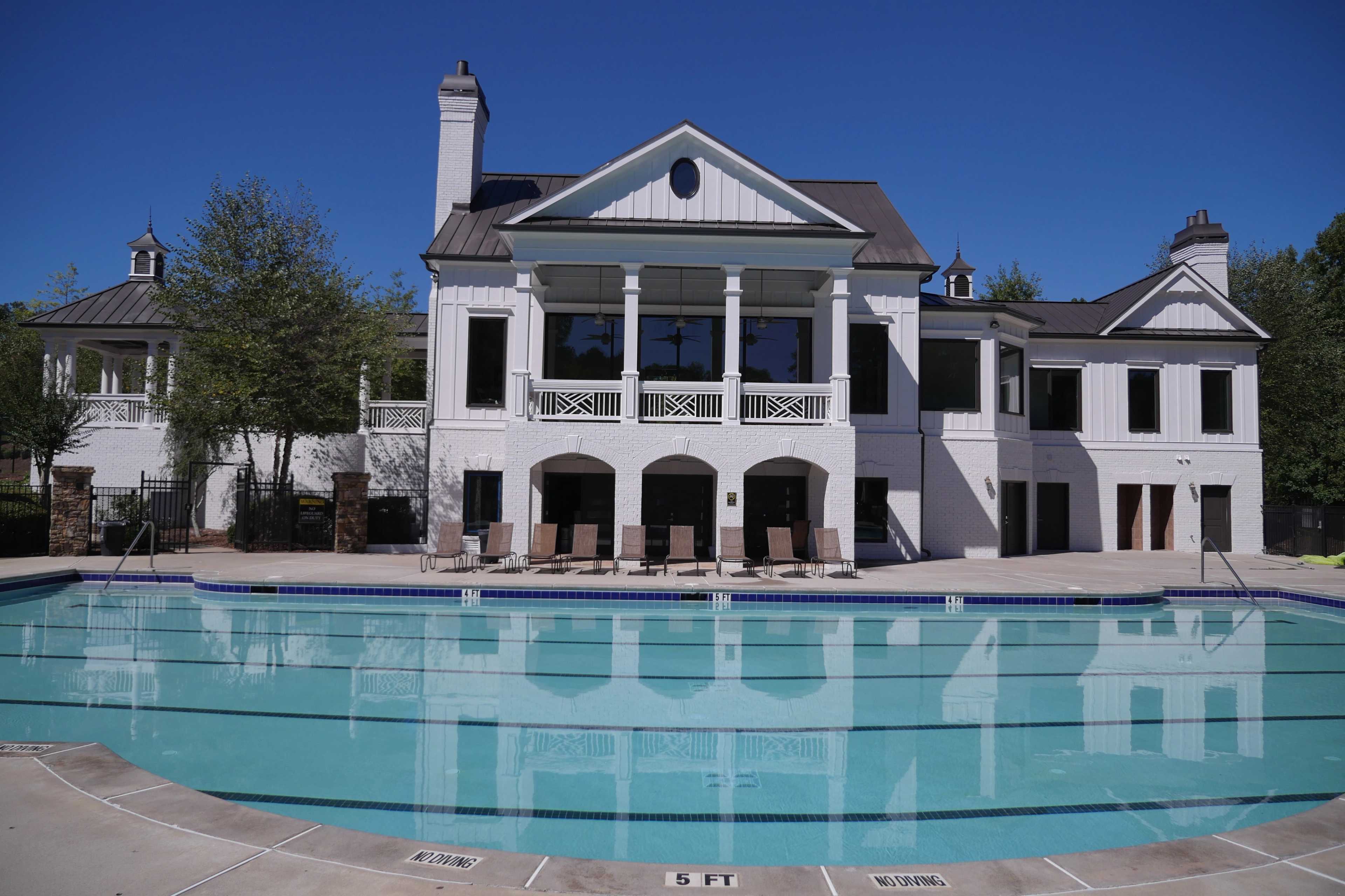Resort-style community pool at Riverwood in Dallas Georgia with lounge chairs, clear blue water and white clubhouse backdrop