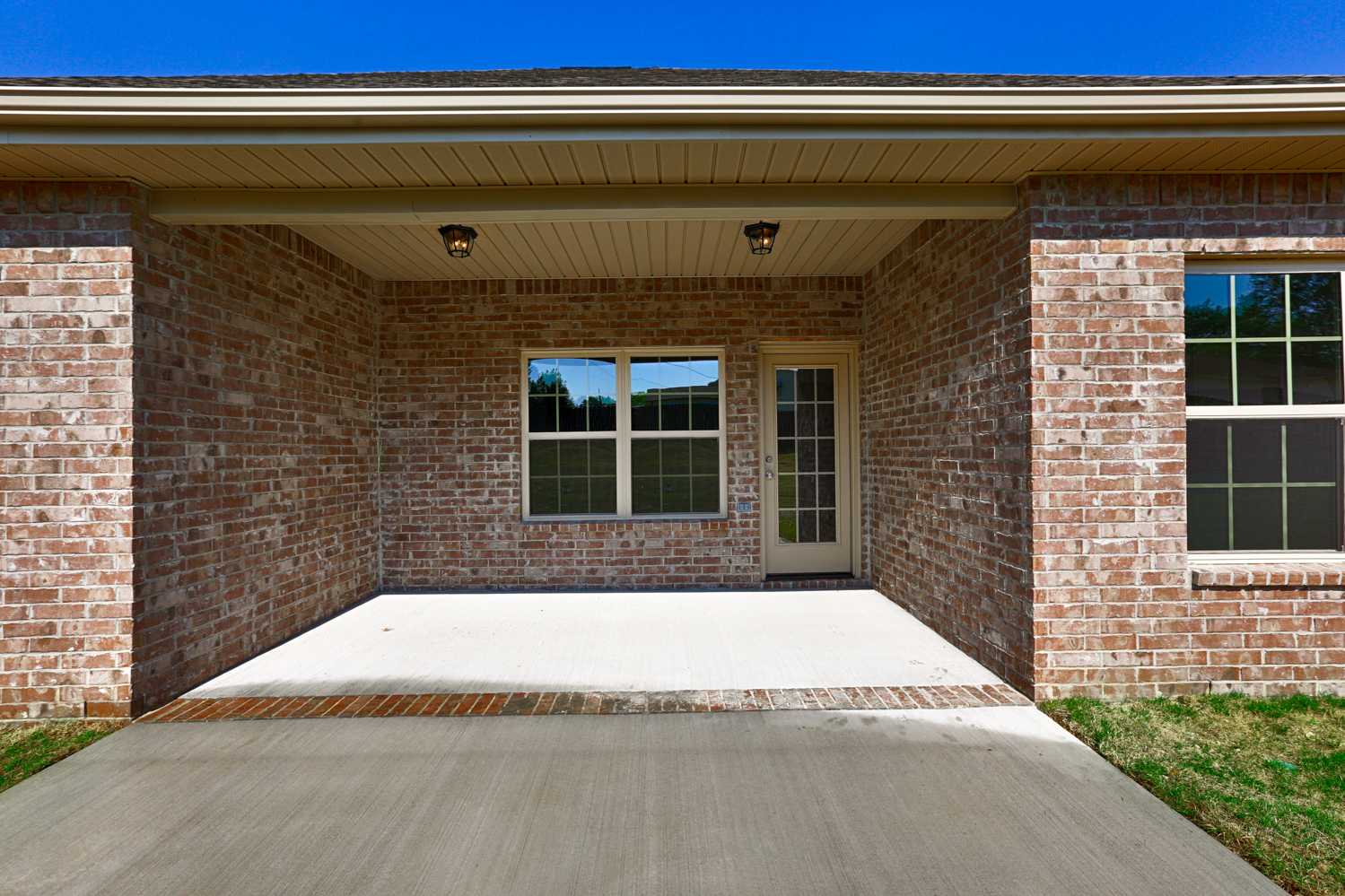 Brick front elevation of The Montgomery home with covered porch, ceiling fans, French doors, and driveway in Meridianville