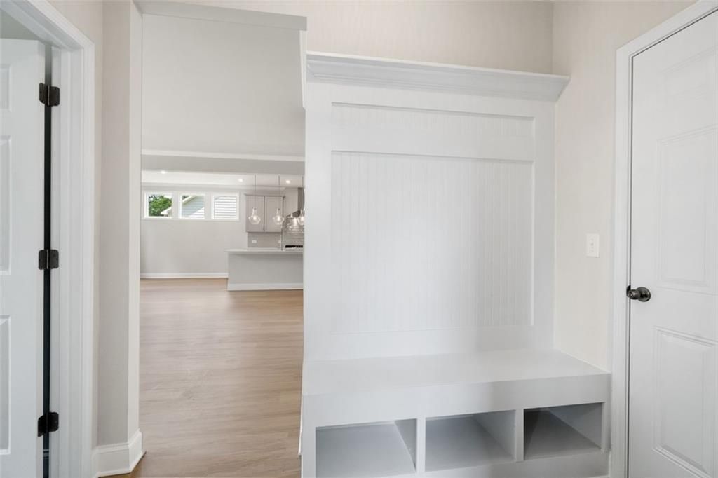 White built-in mudroom with bench and shelves opening to bright kitchen in Davidson Homes The Willow D at Wehunt Meadows, Hoschton