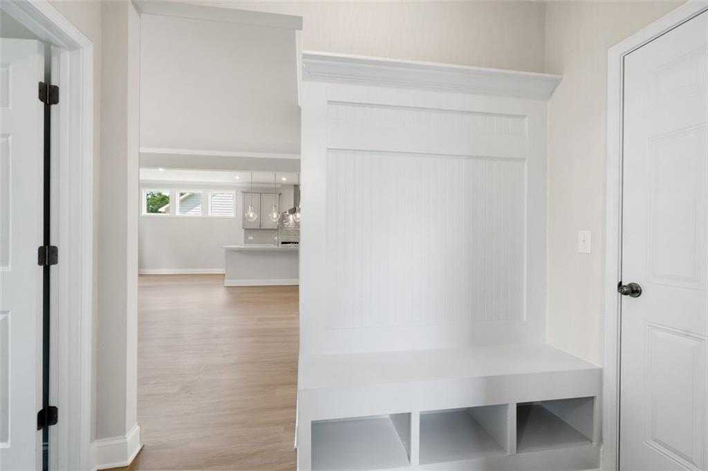 White built-in mudroom with bench and shelves opening to bright kitchen in Davidson Homes The Willow D at Wehunt Meadows, Hoschton