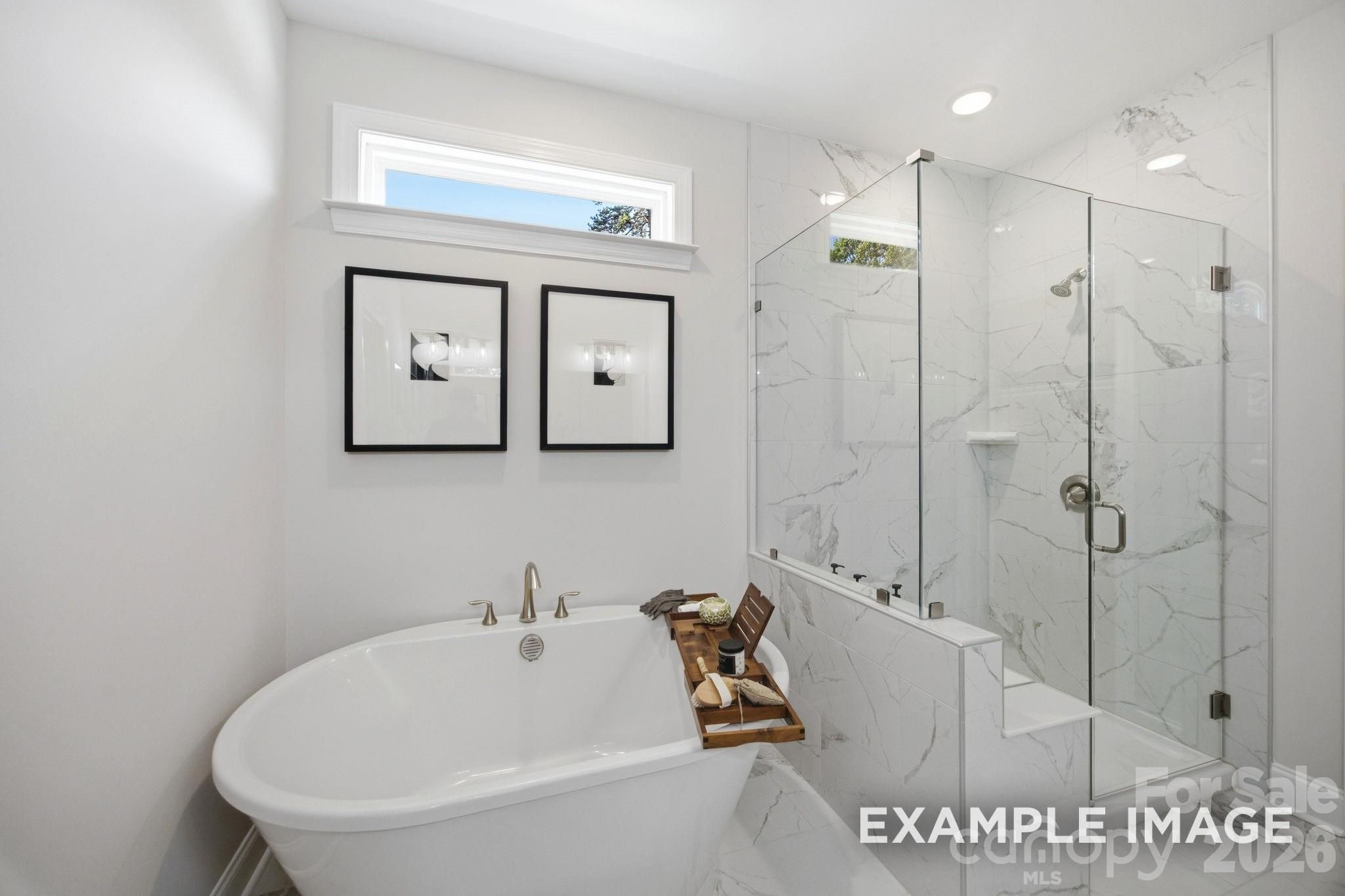 Modern primary bathroom with freestanding soaking tub and glass-enclosed marble shower in Hickory B II floor plan, Windgate.