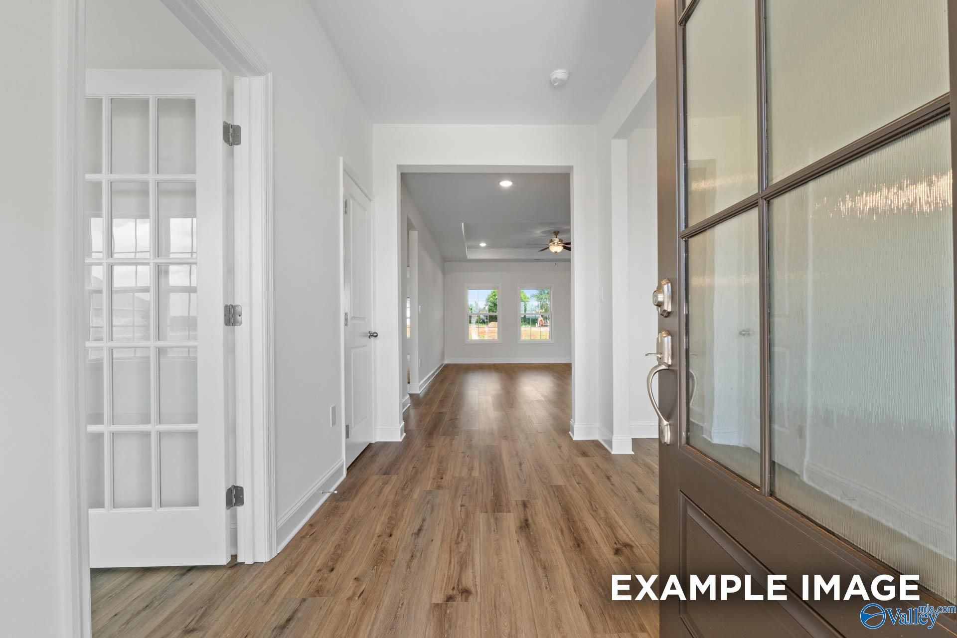 Elegant foyer with glass-paneled doors, hardwood floors, and open hallway in Davidson Homes The Oxford, Huntsville, AL
