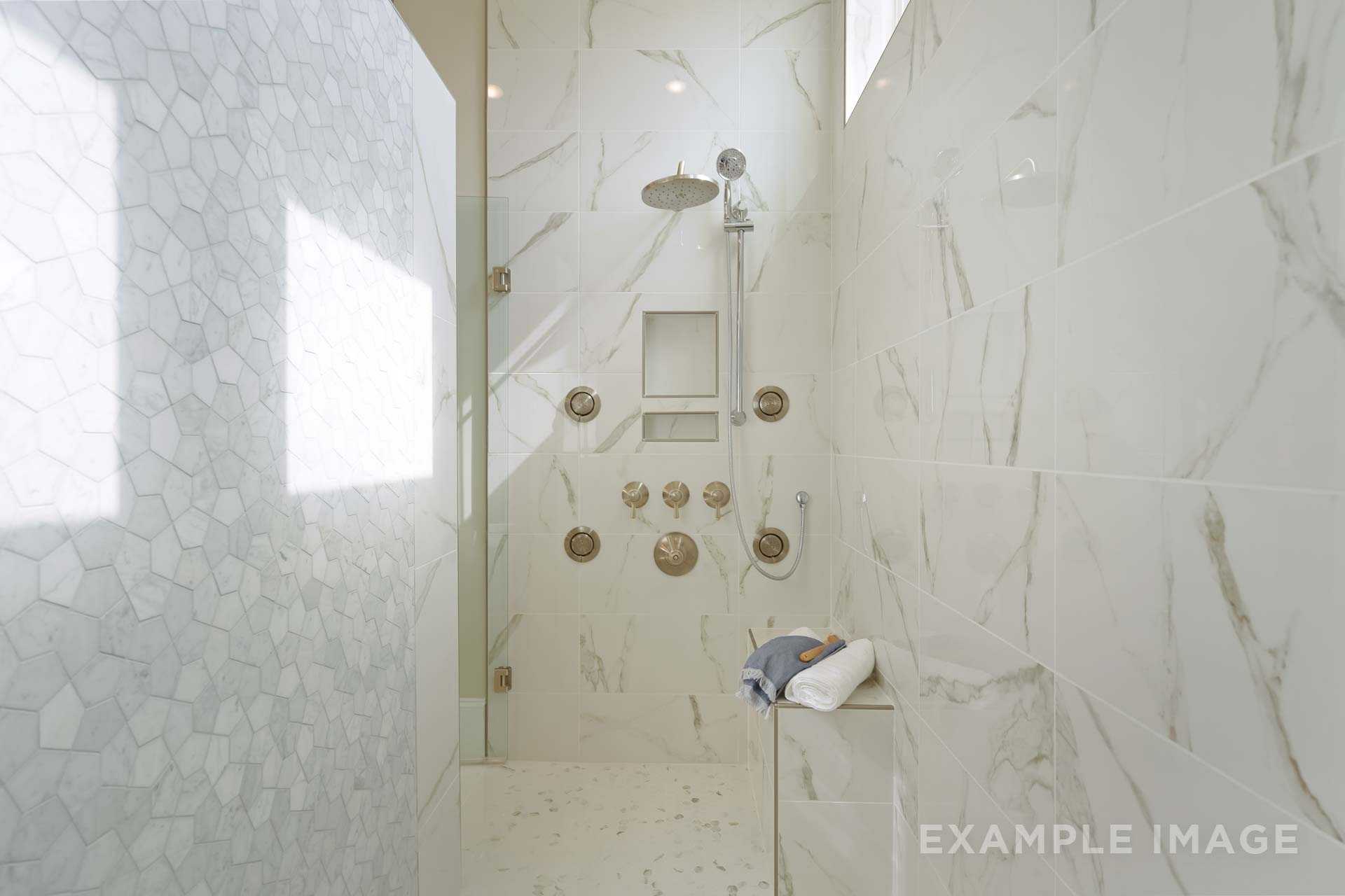 Spacious walk-in shower in The Seaside master bath featuring white subway tiles, rain showerhead, body jets, and built-in bench