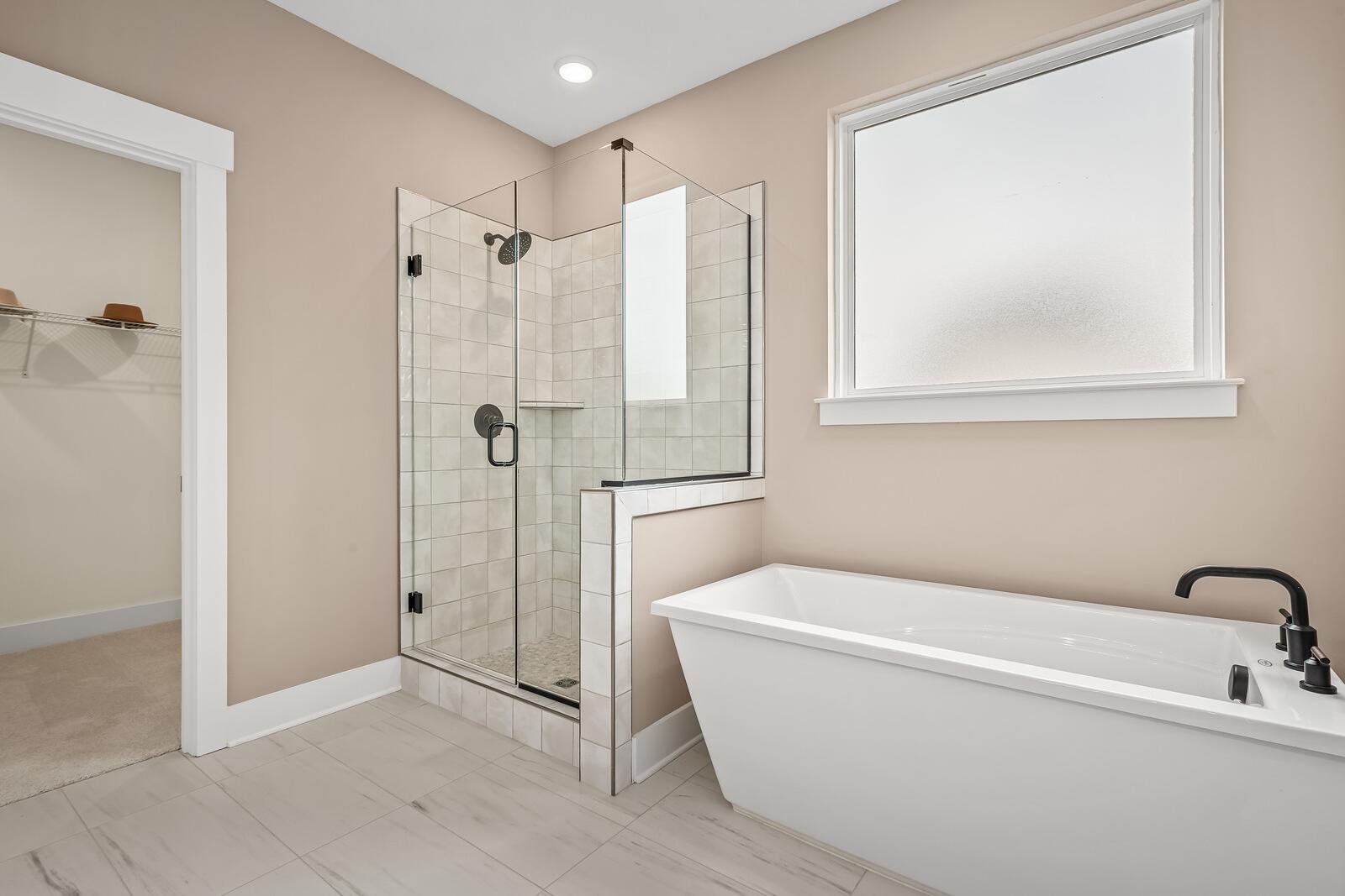 Spacious master bathroom in The Ridgeport with glass walk-in shower, freestanding tub, and neutral tones