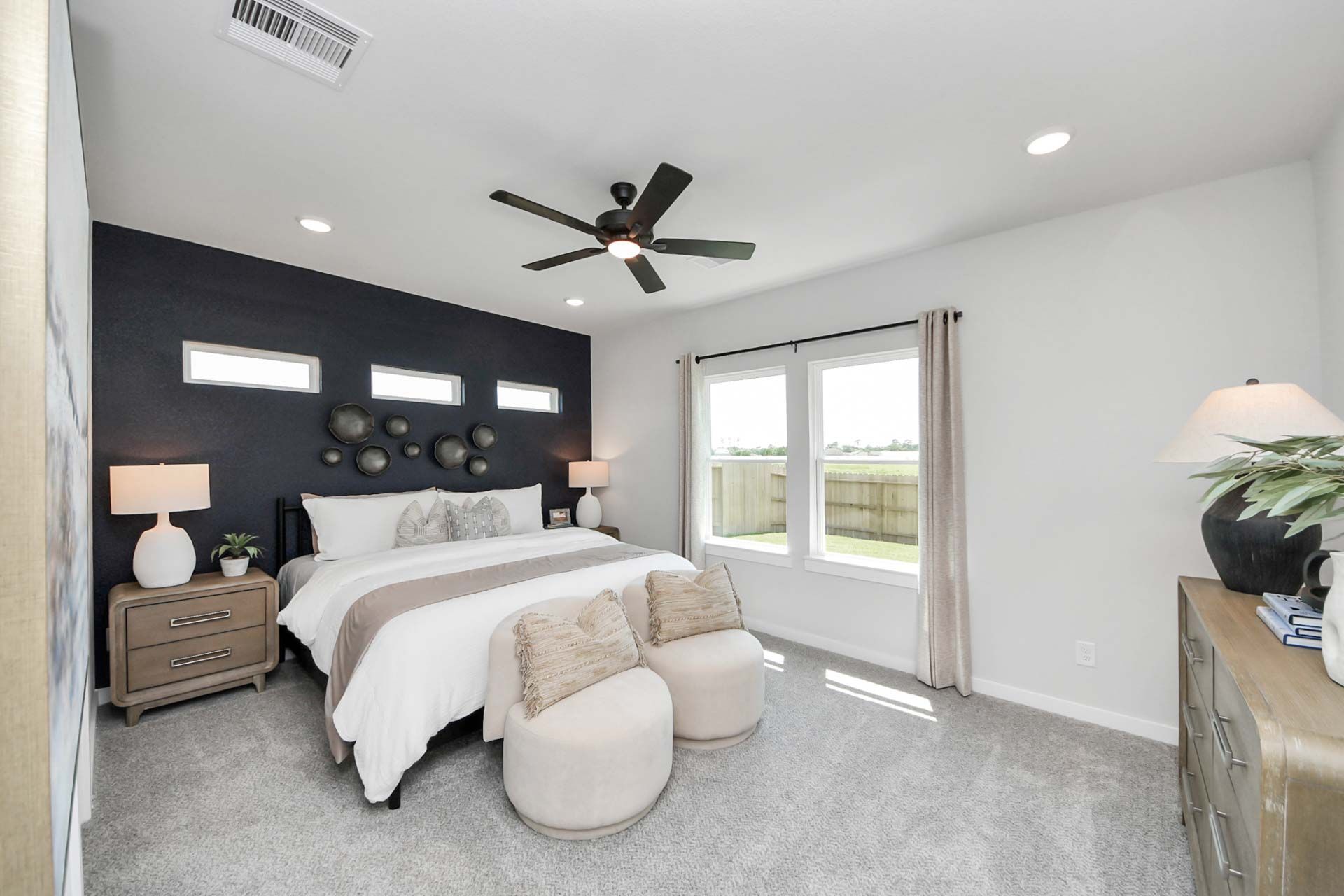 Spacious primary bedroom at Enclave at Newport in Crosby, TX by Davidson Homes with a dark accent wall and plush furniture.