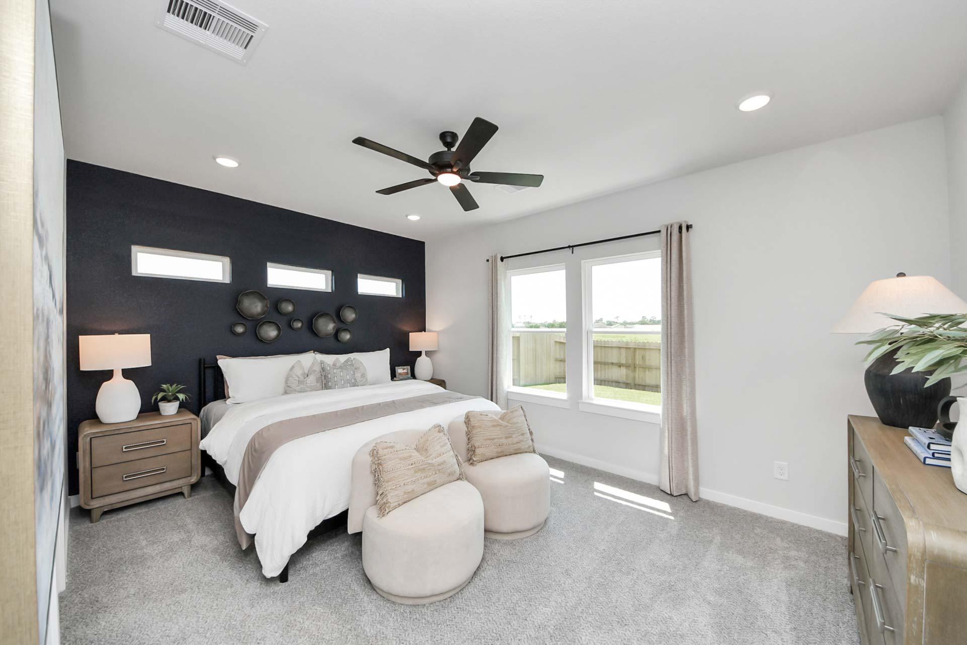Spacious primary bedroom at Enclave at Newport in Crosby, TX by Davidson Homes with a dark accent wall and plush furniture.