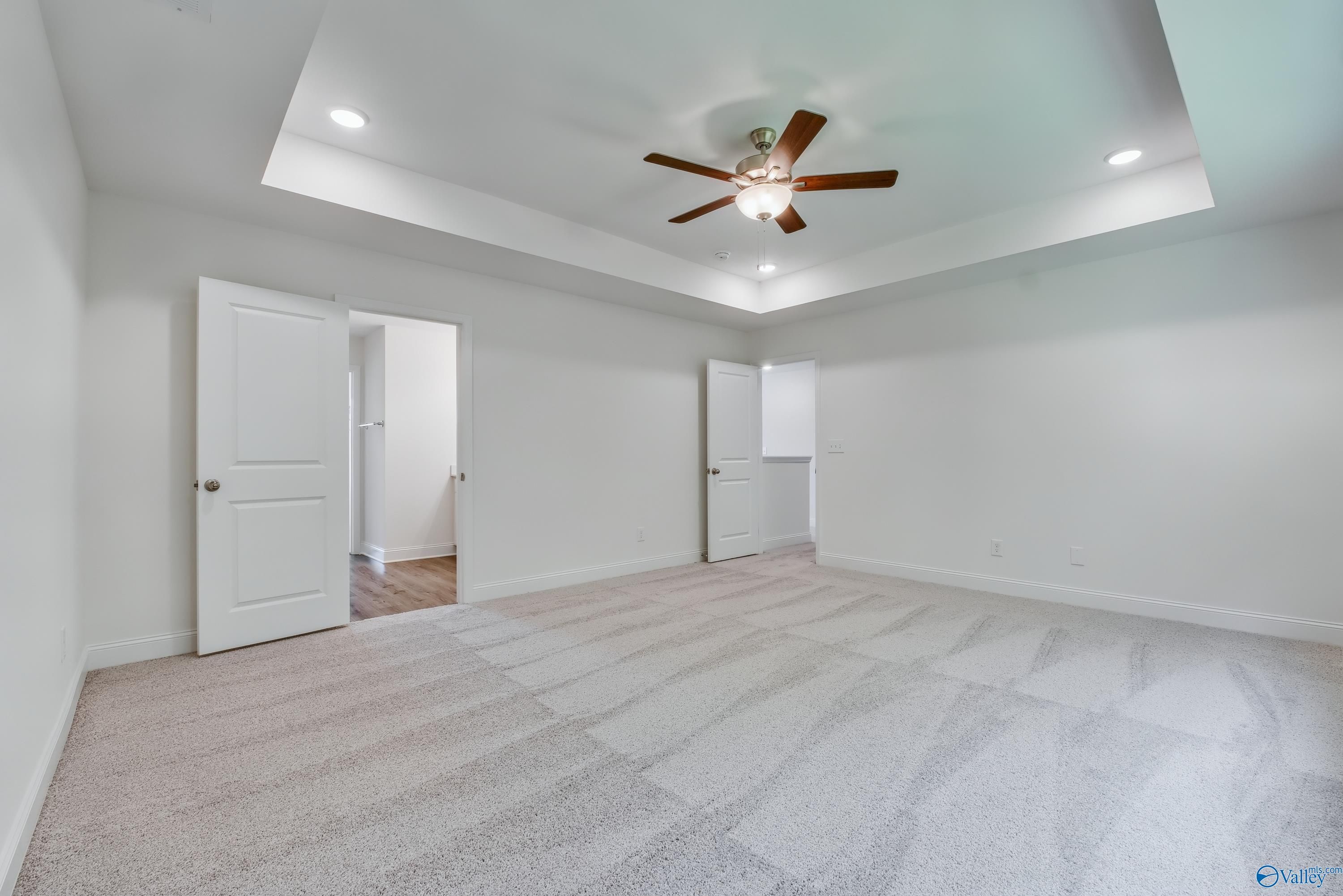 Spacious master bedroom with tray ceiling, lighted ceiling fan, and adjacent bath in Davidson Homes The Shelby A, Arab, Alabama
