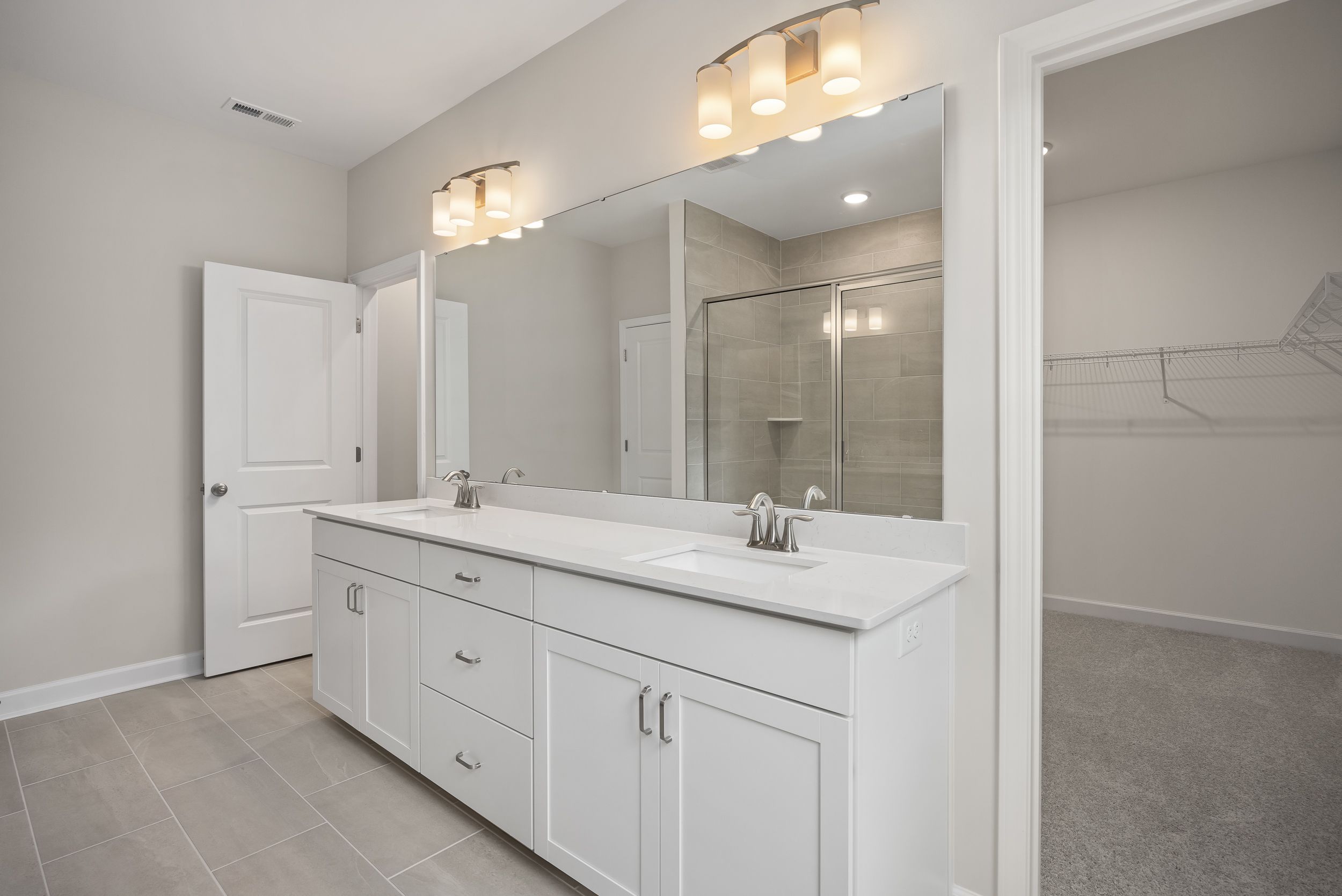 Luxurious master bathroom in The Beech A featuring white double vanity, large mirror, and glass walk-in shower