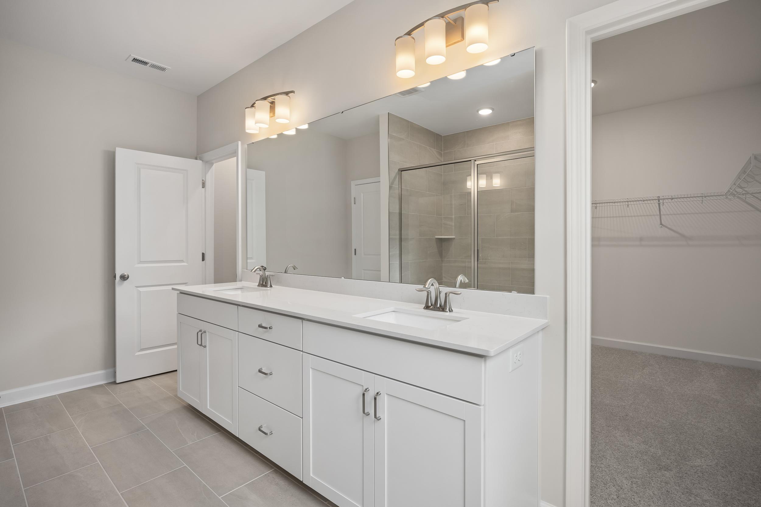 Luxurious master bathroom in The Beech A featuring white double vanity, large mirror, and glass walk-in shower