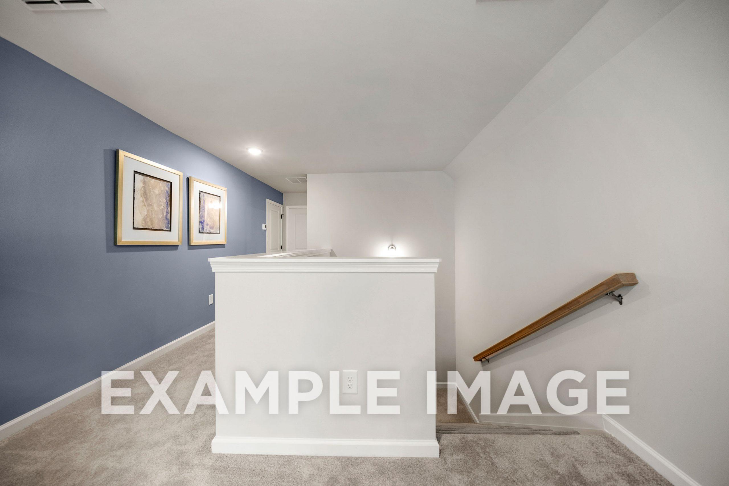 Spacious upstairs hallway in The Hickory Davidson Homes with blue accent wall, framed artwork, white balustrade, and oak handrail, Winder GA