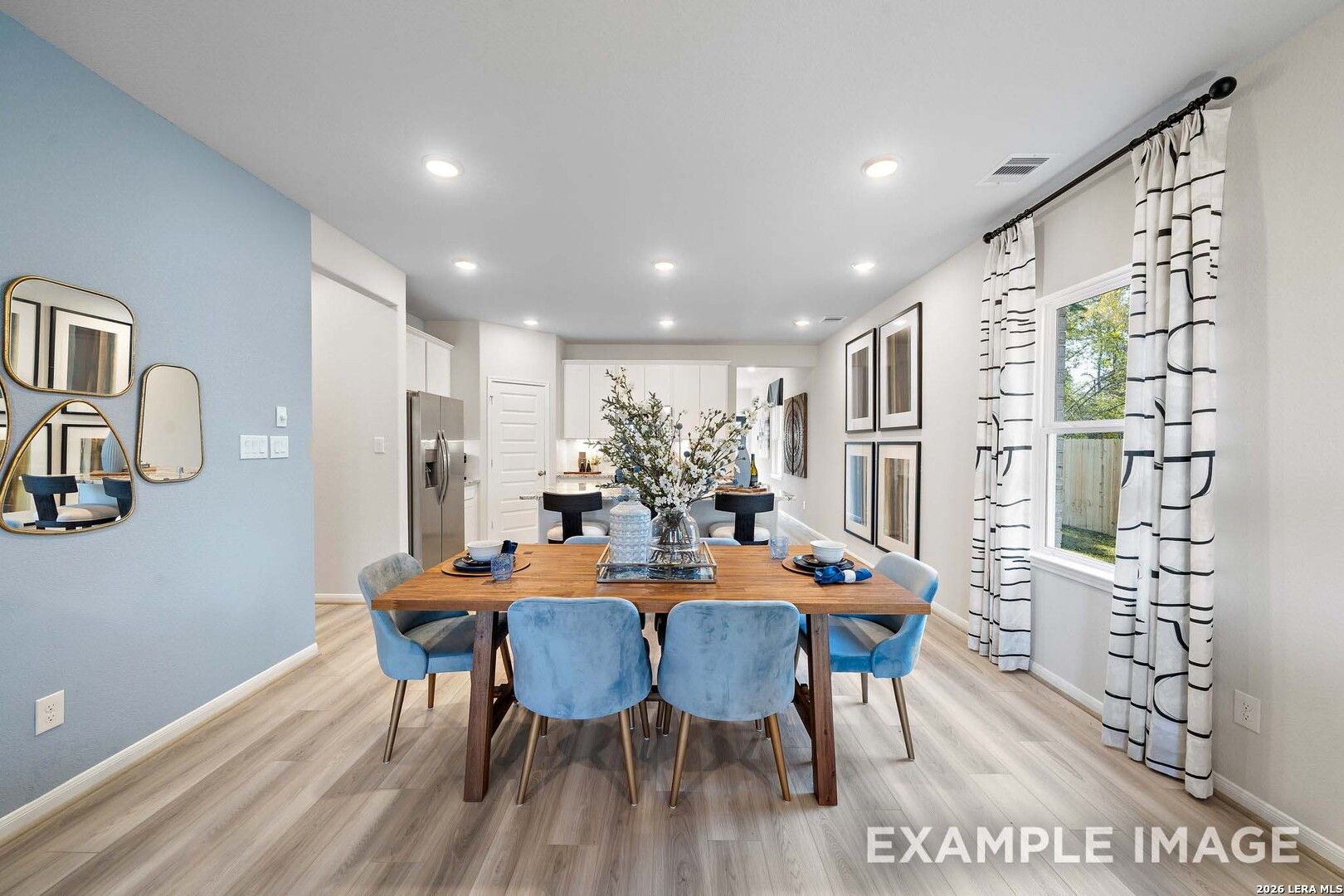 Modern dining area with blue velvet chairs and wood table in The San Marcos F floor plan at Rayburn Valley, San Antonio.