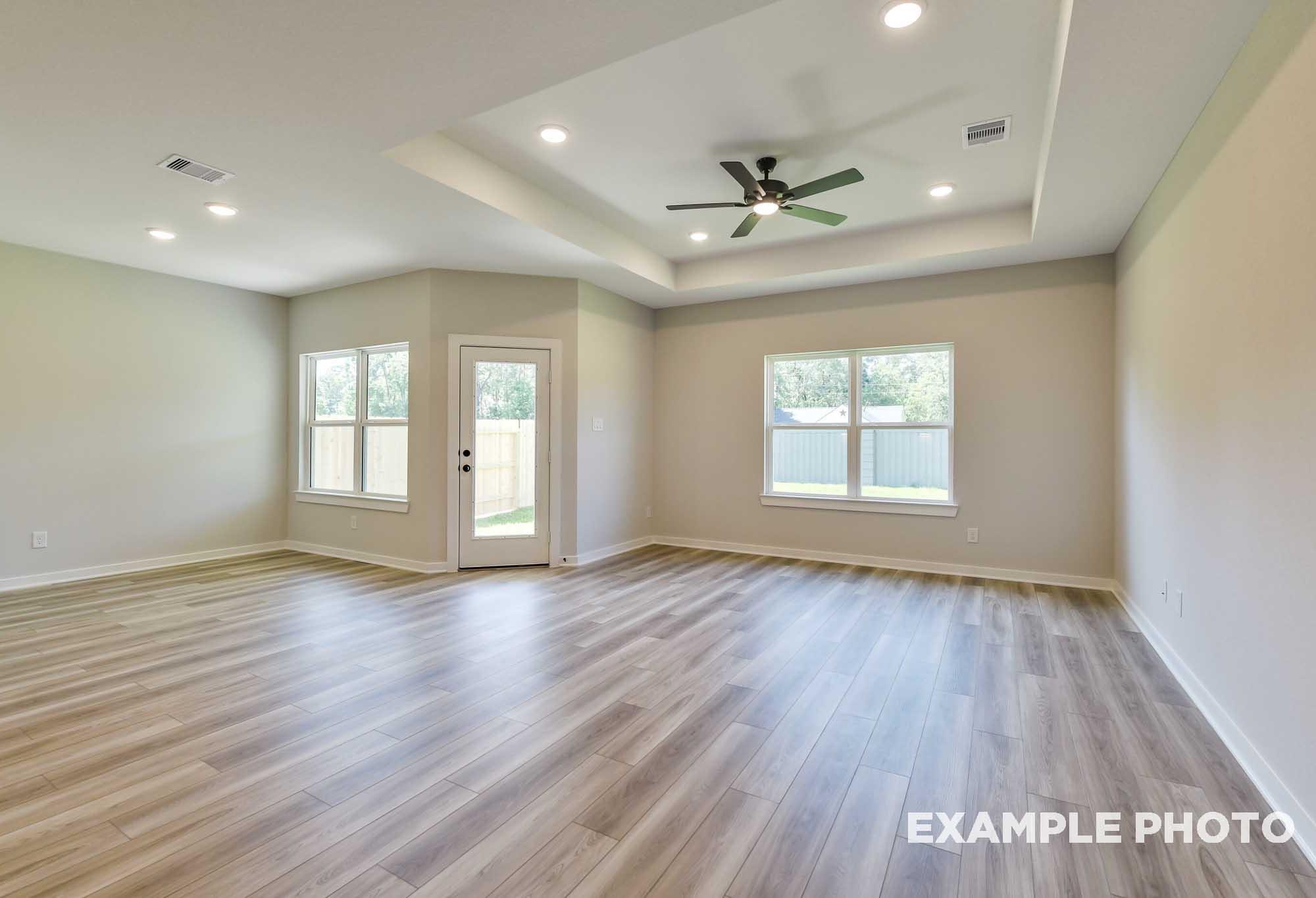 Spacious open-concept living area in The Daphne F with large windows, French doors, ceiling fan, and luxury vinyl plank flooring