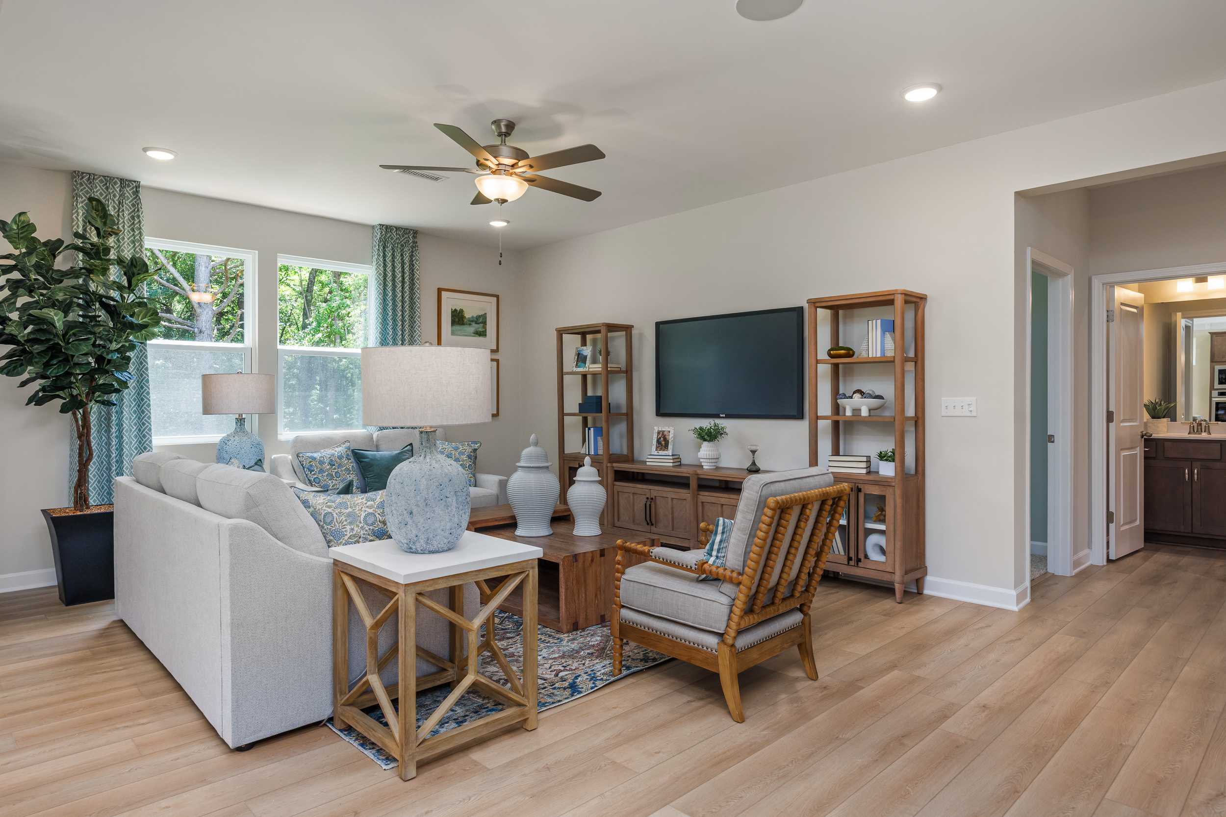 Spacious open-concept living room at Retreat at North Main in Lillington NC featuring white sectional sofa, hardwood floors, and wooden entertainment center