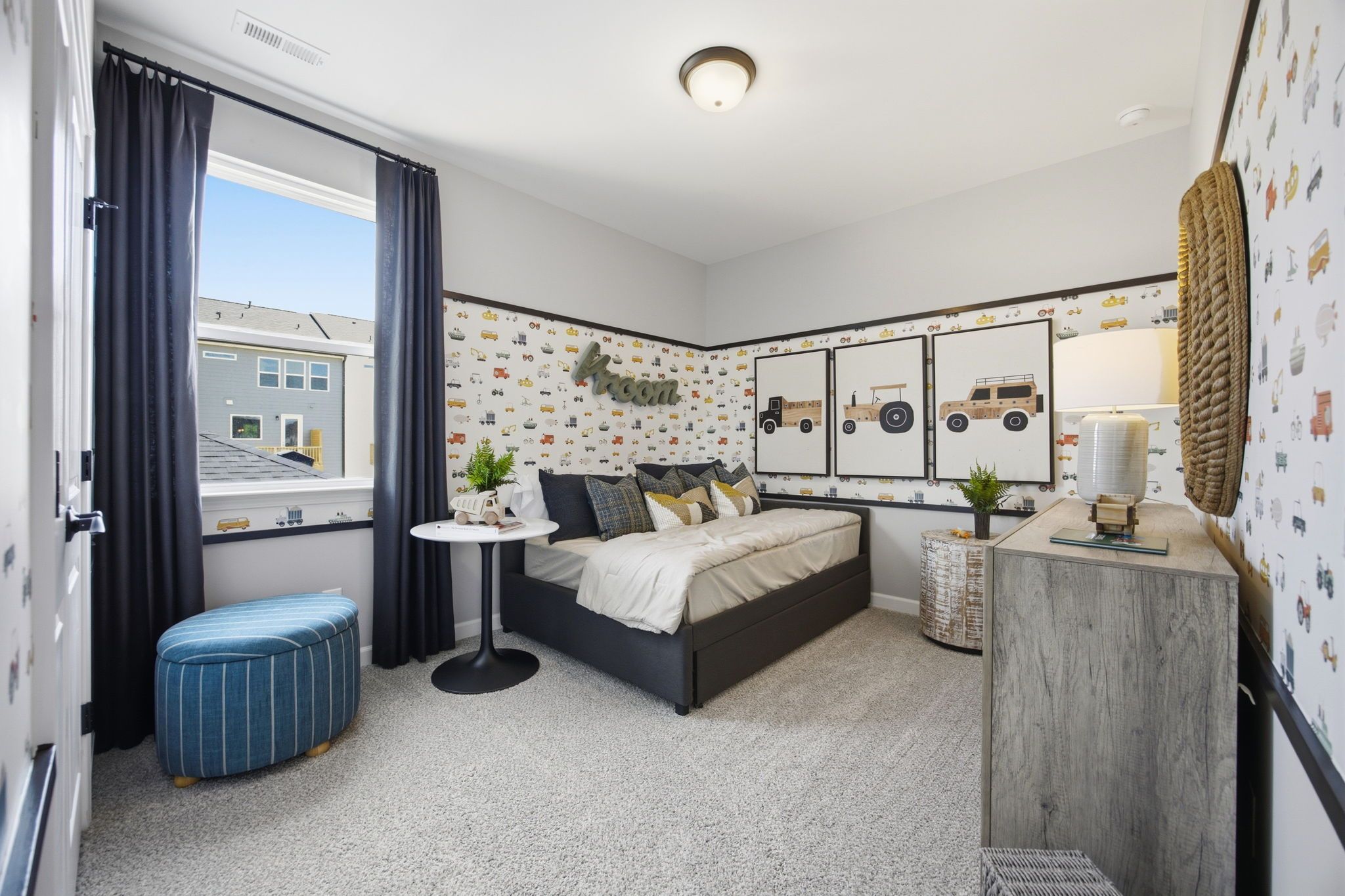 Vehicle-themed boy's bedroom at Forestville Yard in Knightdale NC with trundle bed, truck wallpaper and blue curtains