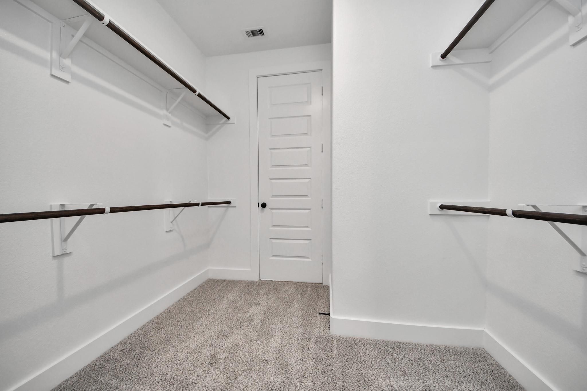 Spacious walk-in closet with built-in shelving in The Laguna C floor plan at Sunterra, Katy, Texas.