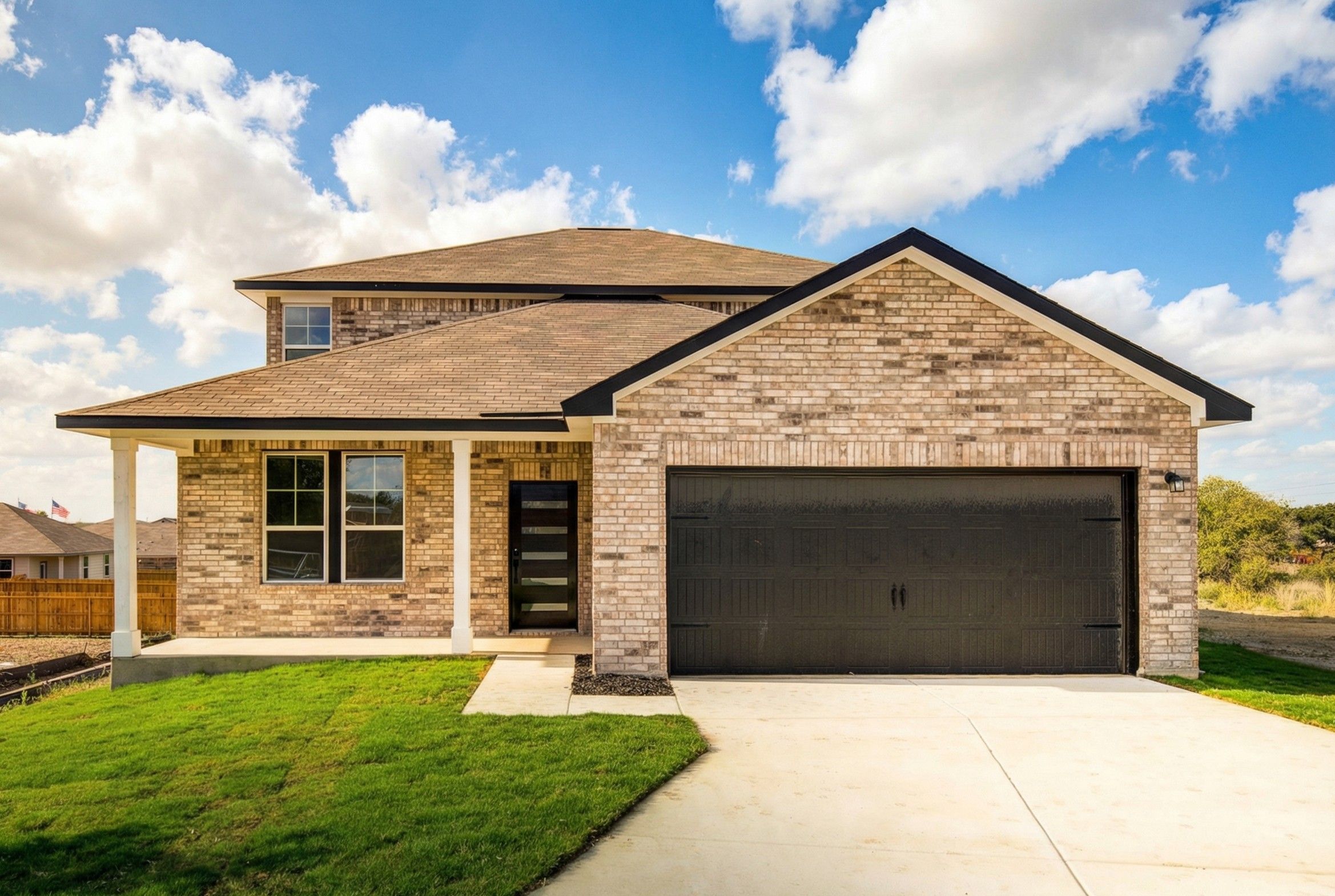 Two-story brick home exterior at Hickory Ridge in Elmendorf Texas by Davidson Homes with covered porch and attached garage