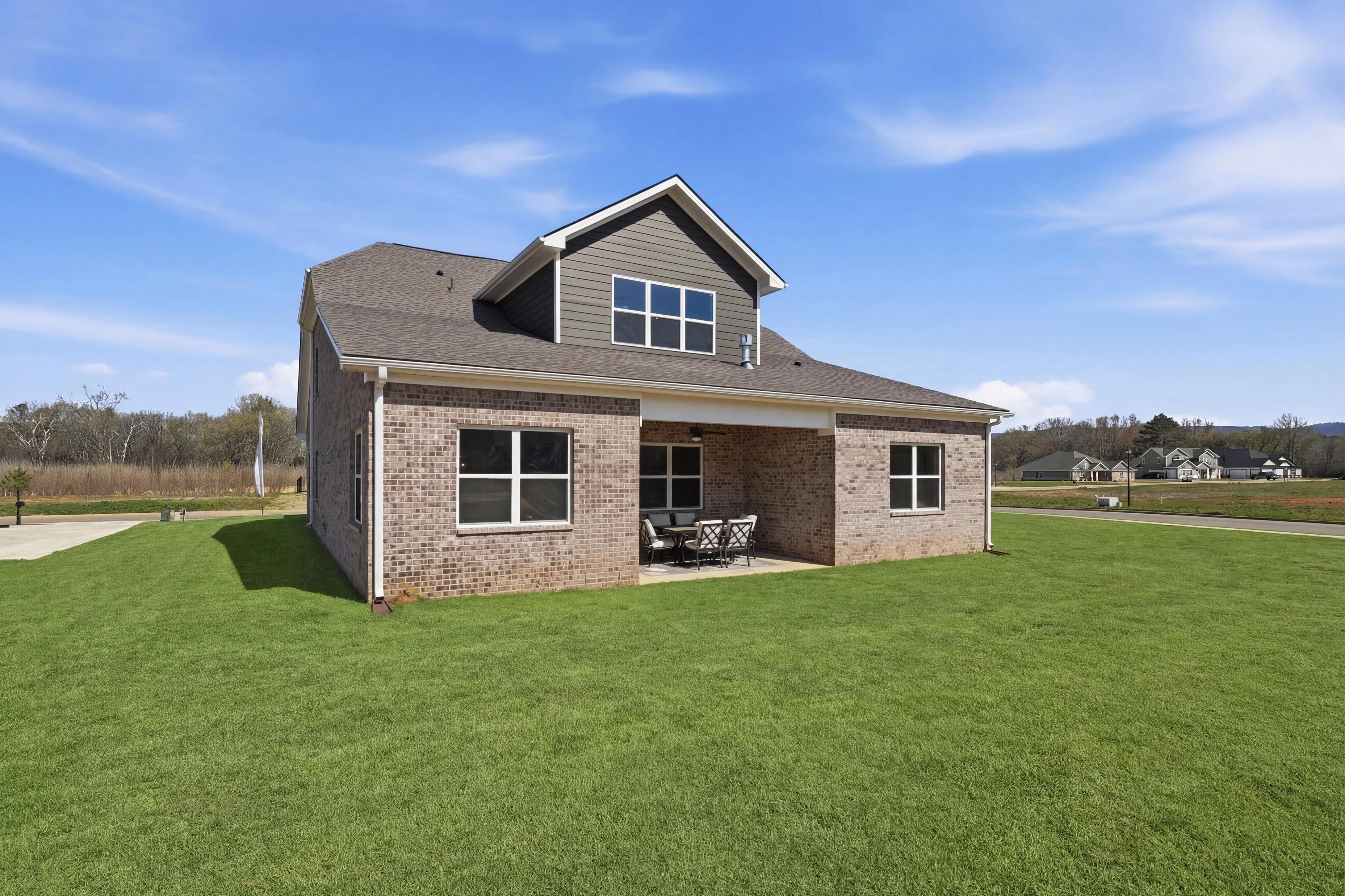 Contemporary brick home exterior with covered side porch and seating at The Meadows at Hampton Cove, Owens Cross Roads AL