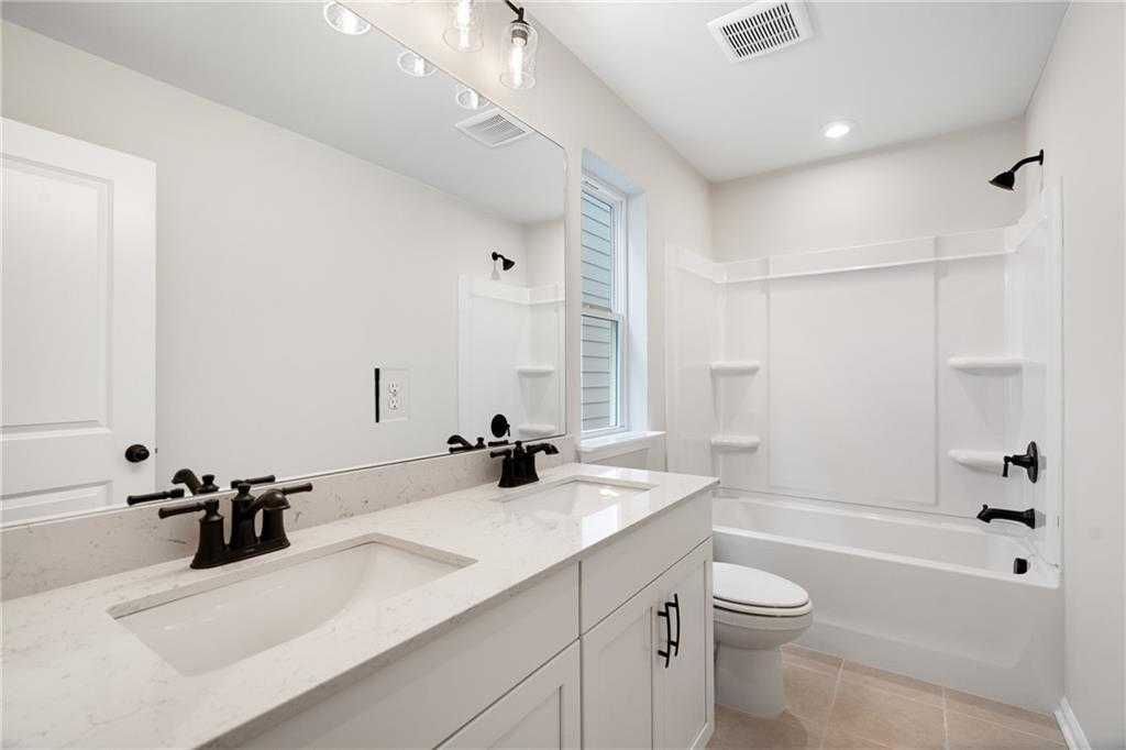 Modern master bathroom with double vanity, soaking tub, and large mirror in Davidson Homes The Marion A, Kennesaw, Georgia