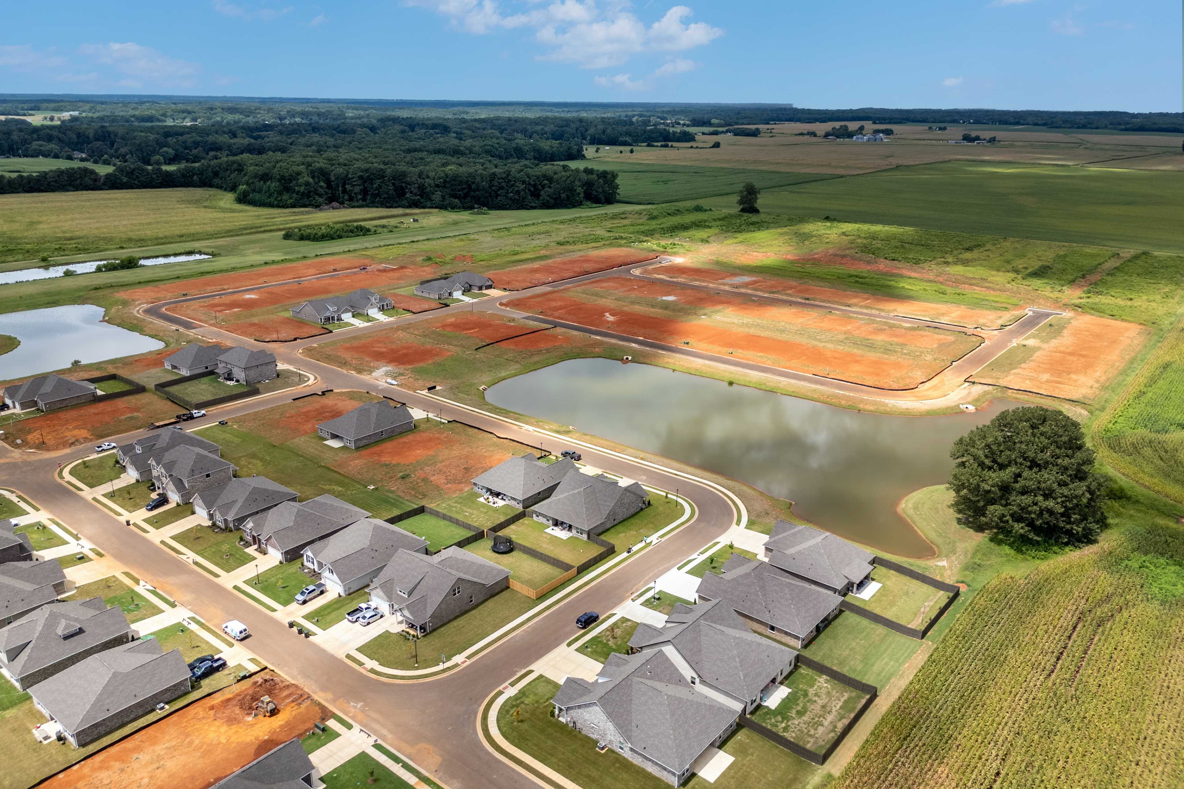 Aerial view of Kendall Downs neighborhood in Toney Alabama by Davidson Homes with new gray-roofed homes ponds and green fields