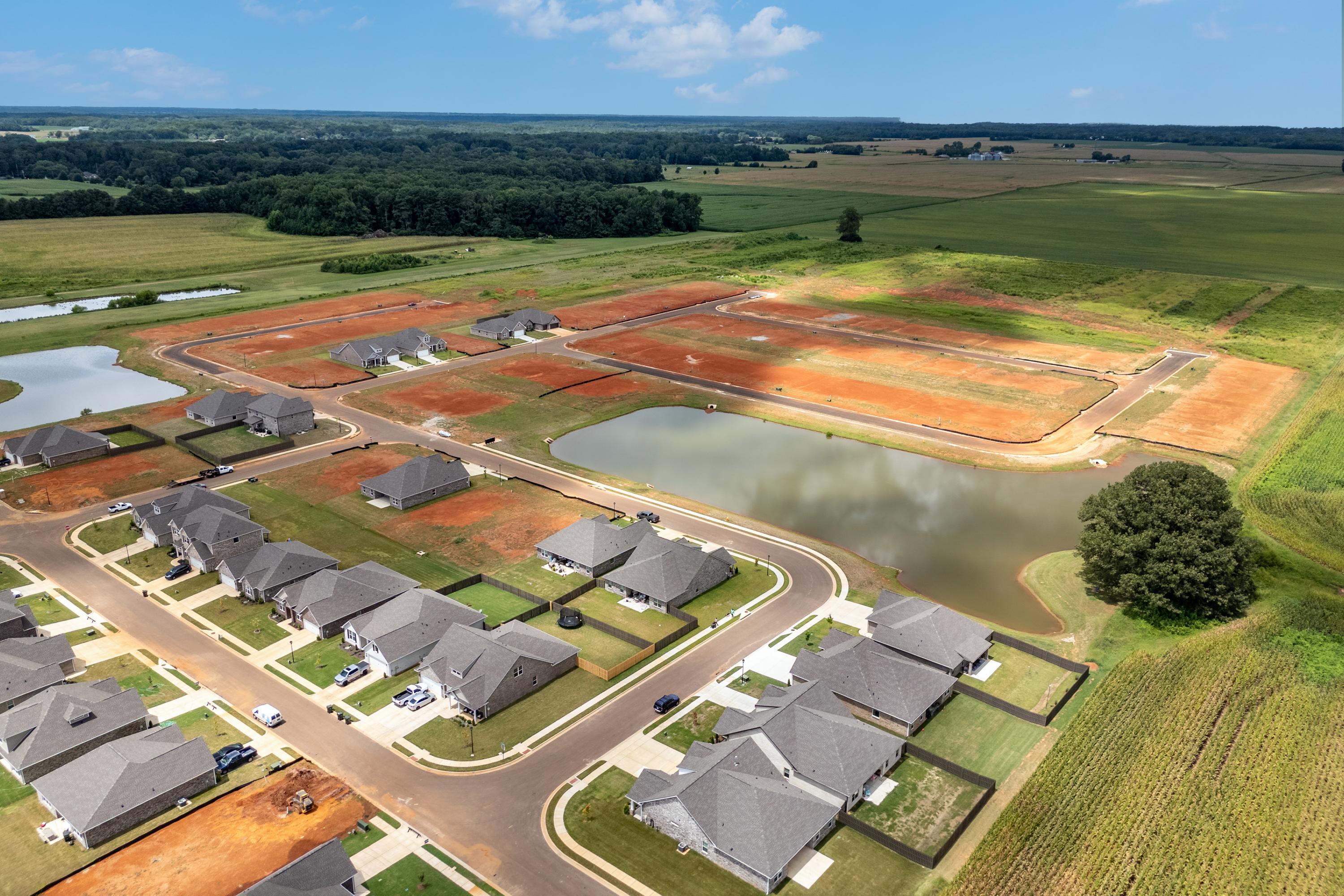 Aerial view of Kendall Downs neighborhood in Toney Alabama by Davidson Homes with new gray-roofed homes ponds and green fields