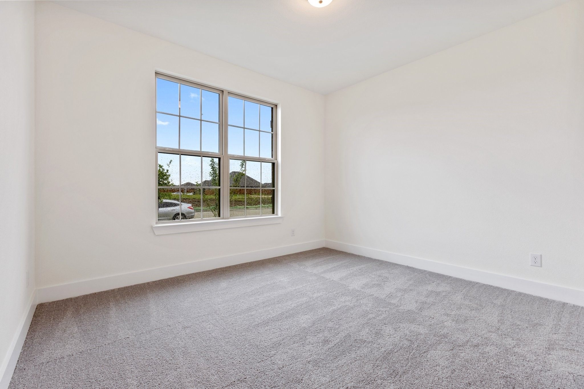 Bright, carpeted bedroom with large window in The Rockford C floor plan at Waverly Estates, Josephine, Texas.