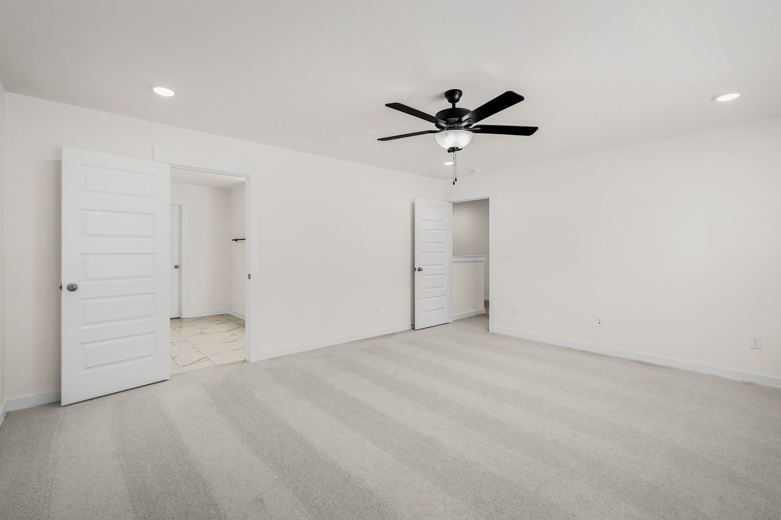 Spacious bedroom with plush carpet and ceiling fan in The Willow floor plan by Davidson Homes in Woods Crossing, Gallatin.