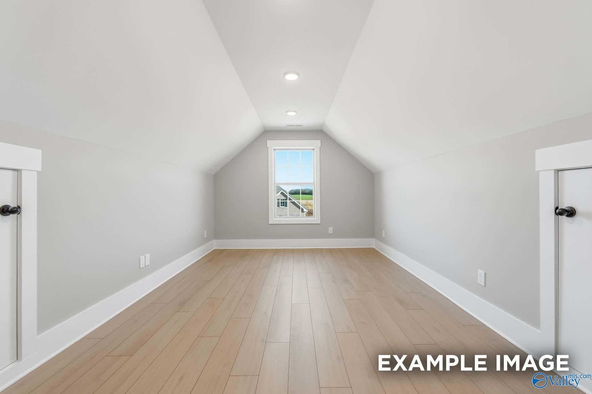 Spacious bonus room featuring vaulted ceiling, gabled window, hardwood floors in The Emory 4-bedroom home by Davidson Homes, Decatur, Alabama