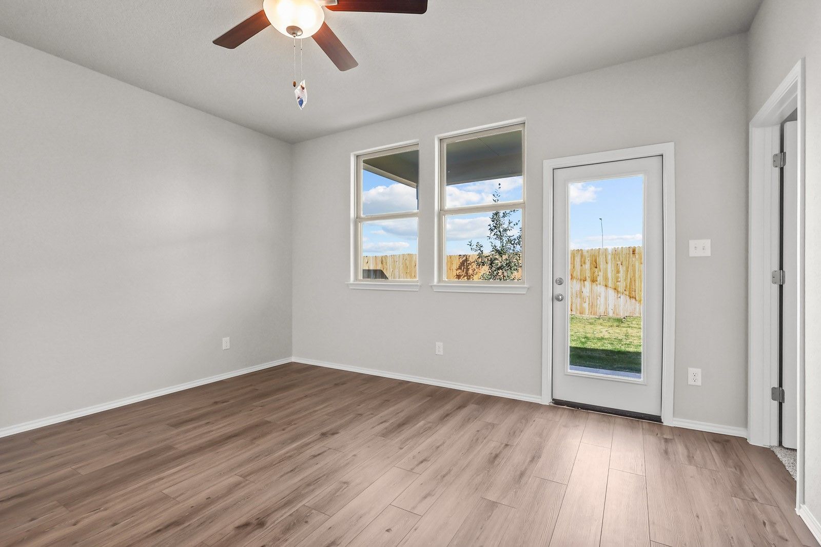 Bright living area with wood-style flooring and backyard access in The Frio G floor plan by Davidson Homes in Heartland, TX