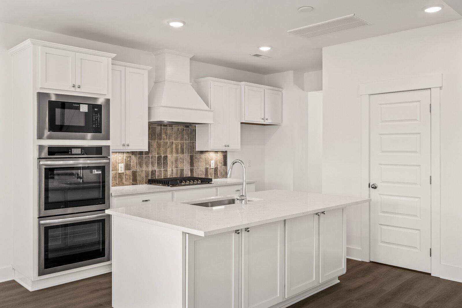 Modern white kitchen with stainless steel double oven, island sink, shiplap backsplash in Davidson Homes The Willow D, Mt. Juliet