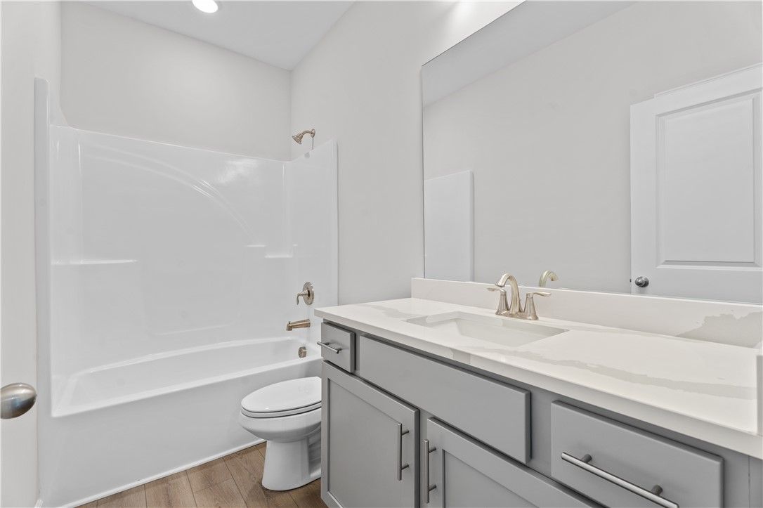 Modern bathroom featuring dual sink vanity, white tub-shower combo, and gray cabinets in Davidson Homes The Luna B, Opelika, Alabama
