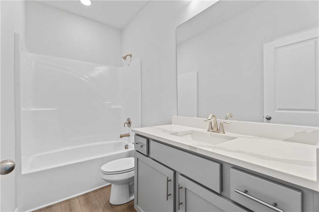 Modern bathroom featuring dual sink vanity, white tub-shower combo, and gray cabinets in Davidson Homes The Luna B, Opelika, Alabama