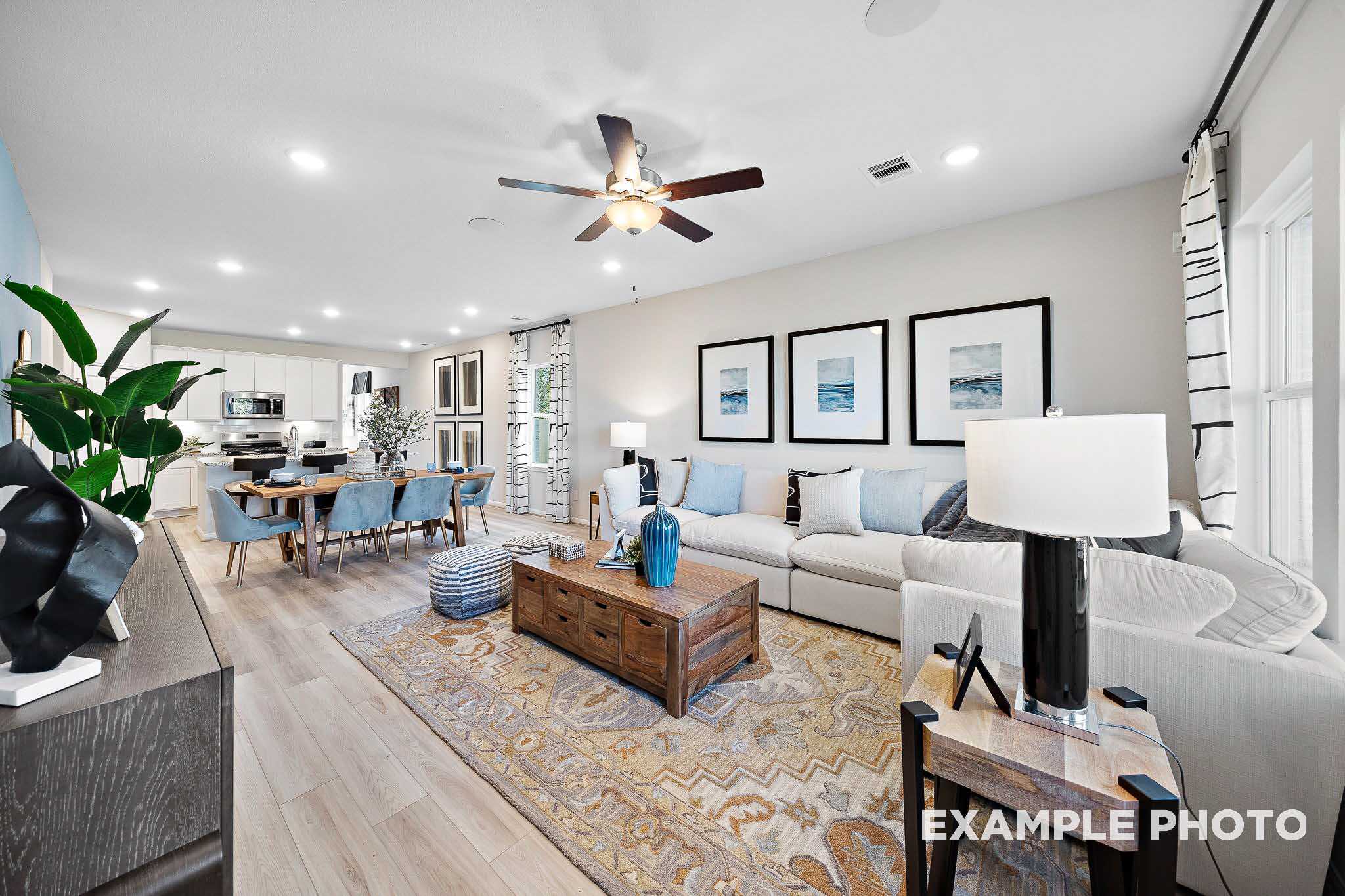 Spacious open-concept living and dining area in The San Marcos B with white sofa, wooden table, coastal art, and natural light