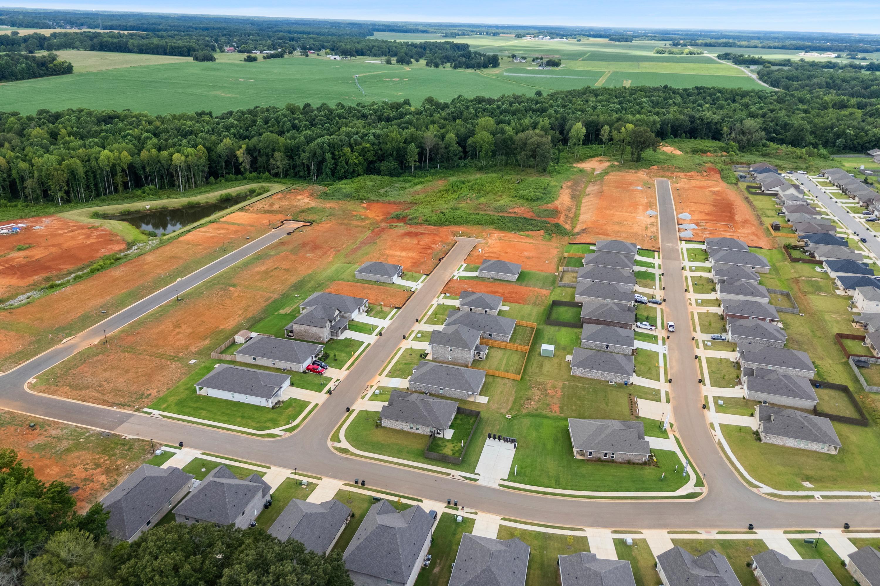 Aerial view of new single-family homes under construction at Wood Trail in Toney, Alabama amid green fields and woods