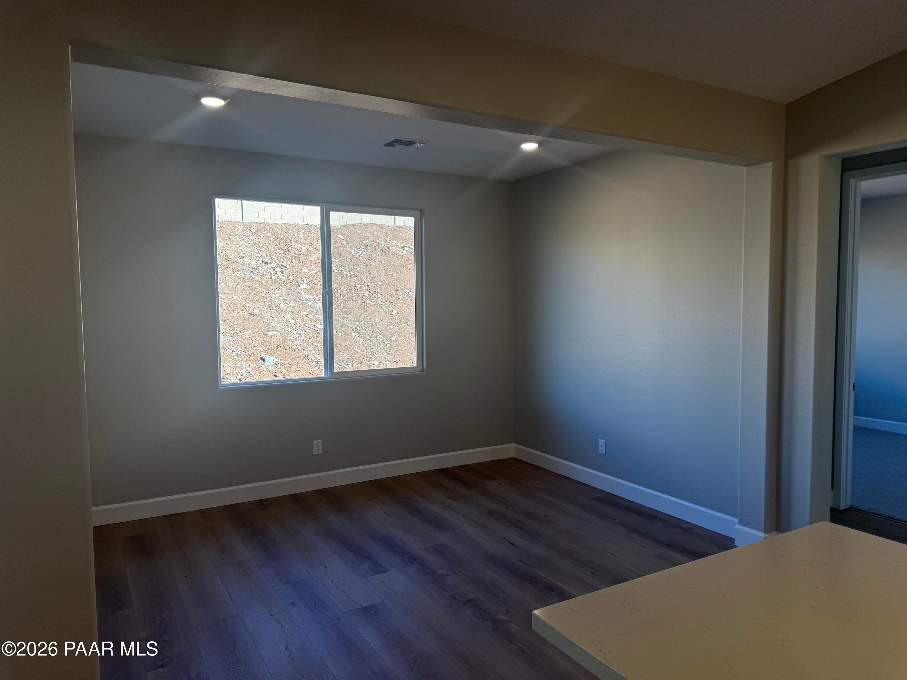 Spacious empty bedroom with large window, neutral walls, recessed lights, and vinyl plank flooring in Evermore Homes The Monarch B, Prescott Valley, AZ