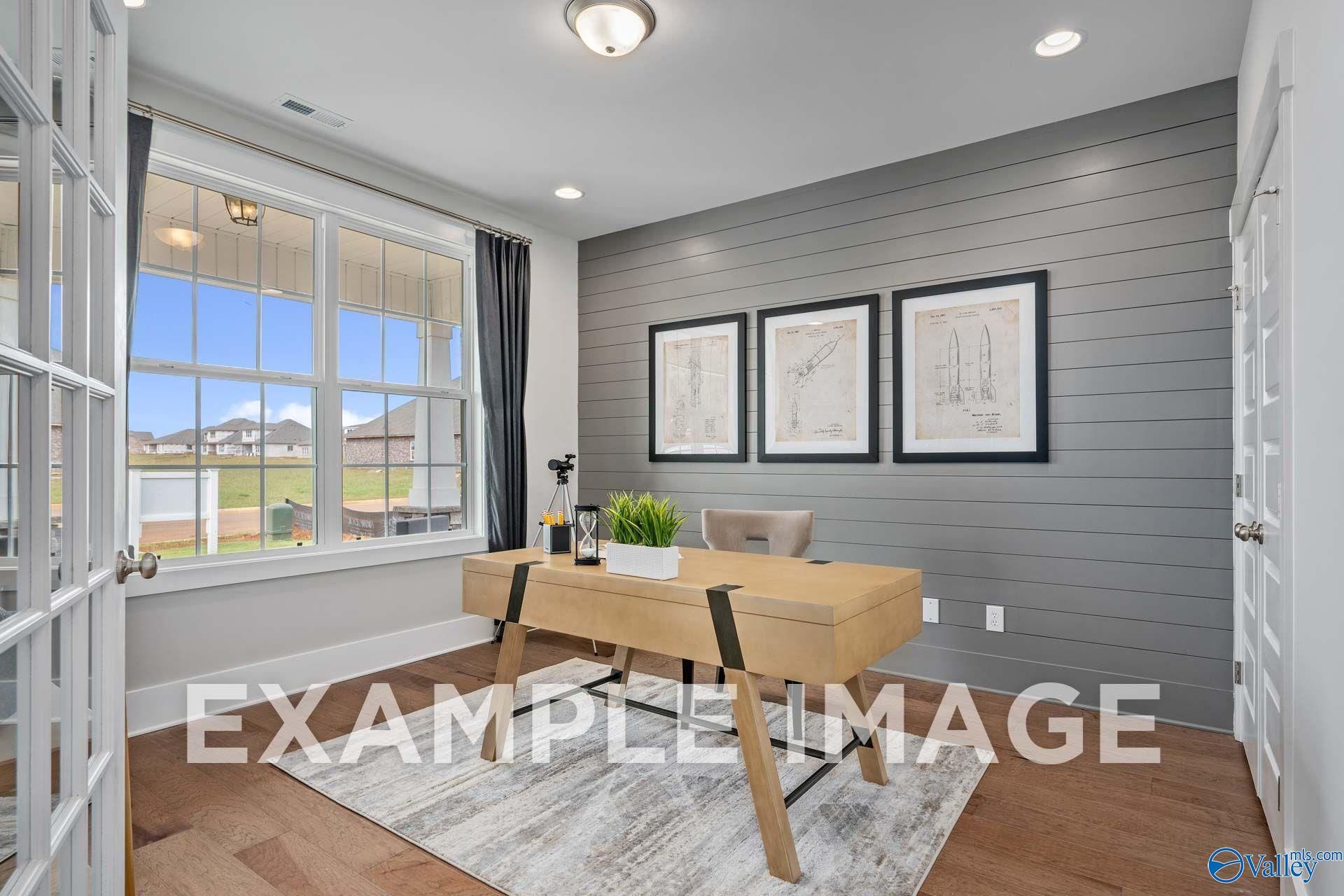 Bright home office with gray shiplap accent wall, wooden desk, and large windows in Davidson Homes The Harrison, Hartselle, Alabama
