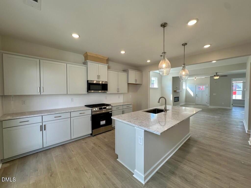Modern open-concept kitchen with white cabinets, quartz island, stainless appliances in Davidson Homes The Burke, Knightdale, NC