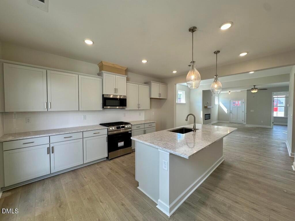 Modern open-concept kitchen with white cabinets, quartz island, stainless appliances in Davidson Homes The Burke, Knightdale, NC